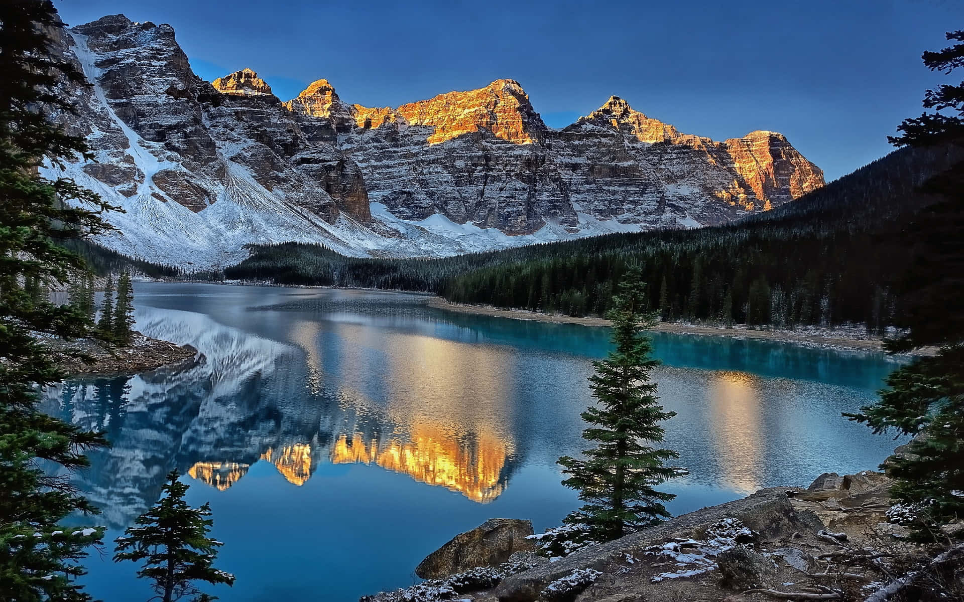Canada 桌布 壁紙 — 寧靜的高山湖泊映照著被常青樹環繞、在金色日出光芒中閃耀的雪山。