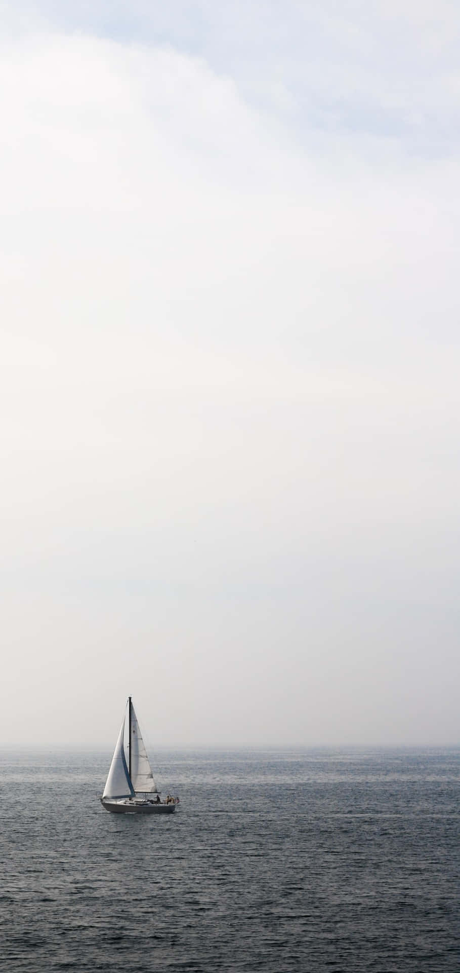多雲天空下平靜海洋上的帆船