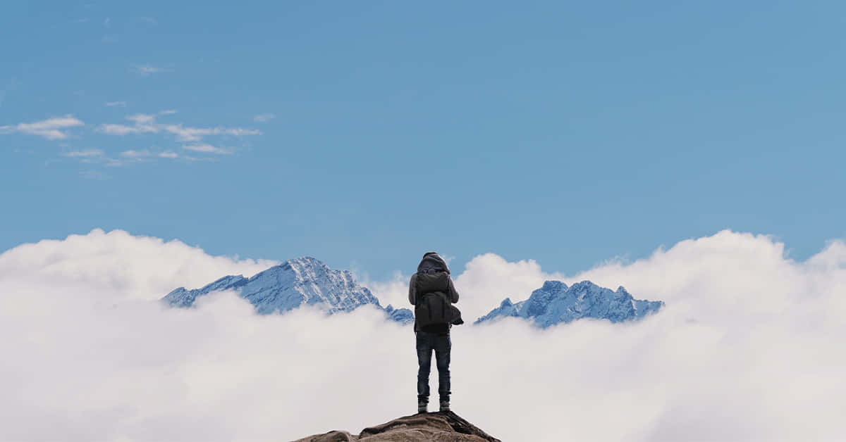 遠足者在雲端山頂上眺望遠處積雪的山峰。