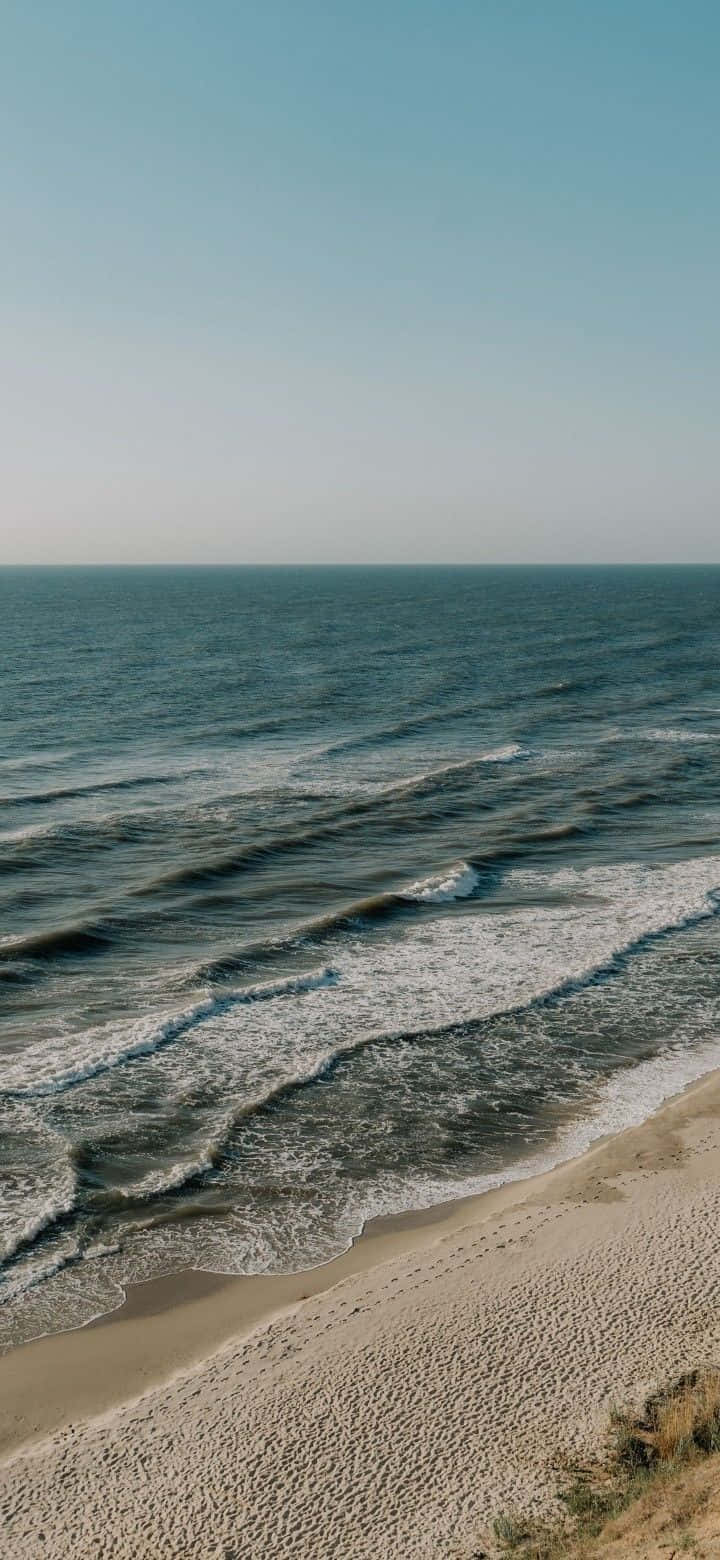 清澈藍天下，海浪輕輕拍打沙灘。