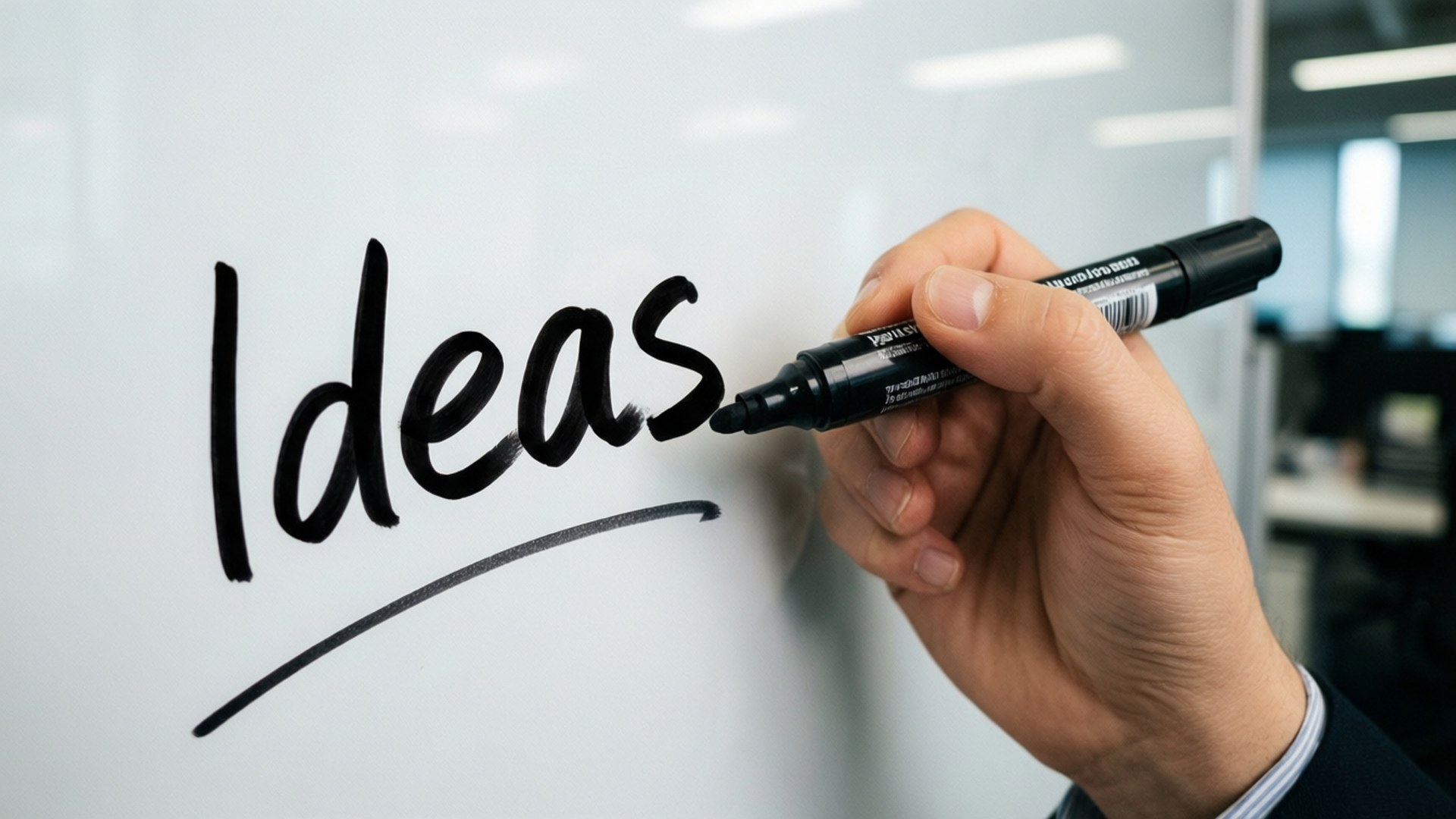 用黑色馬克筆在白板上寫下 Ideas 這個詞的手。