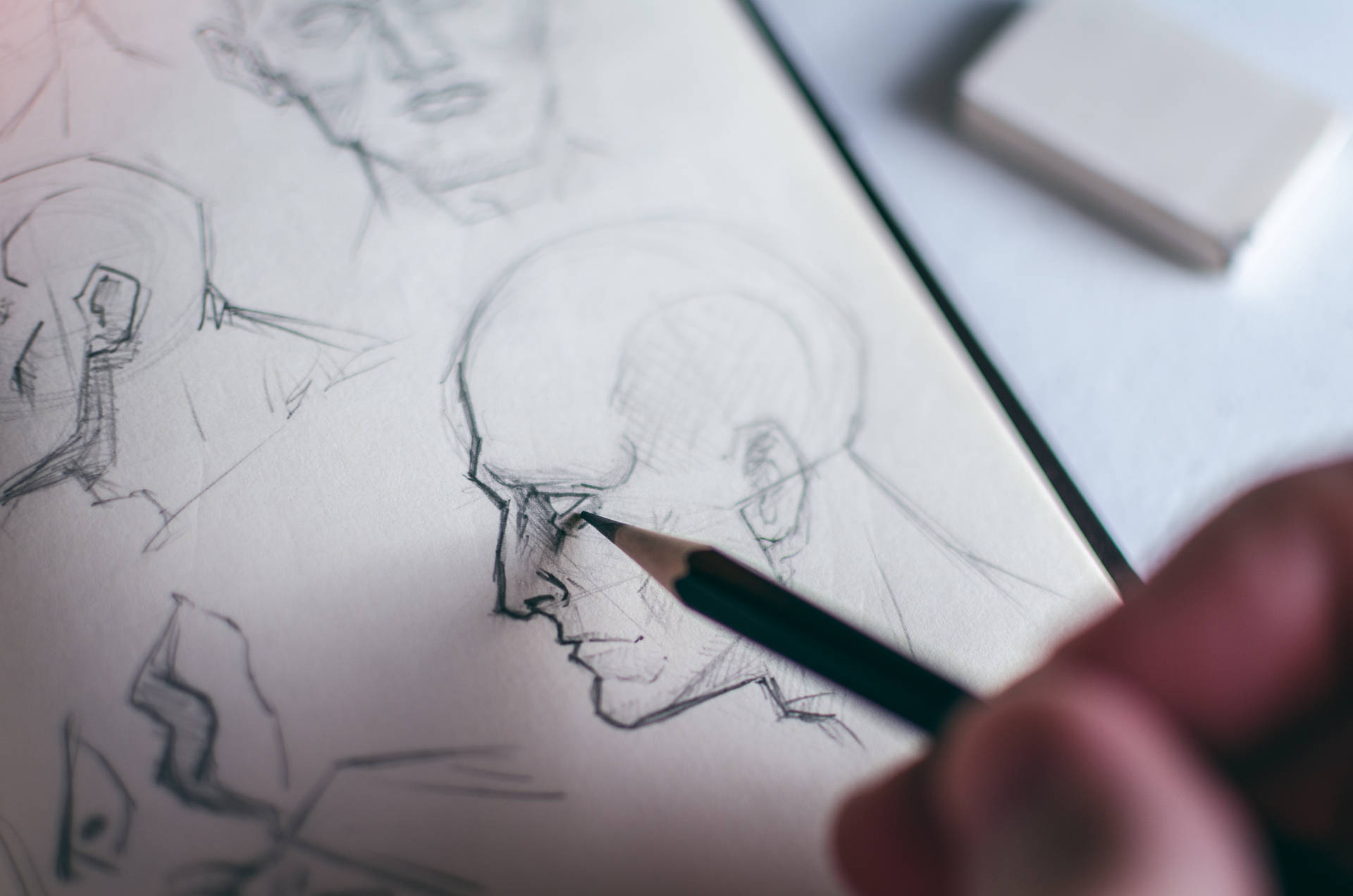 藝術家的手在素描紙上用鉛筆畫一個光頭男人的臉。