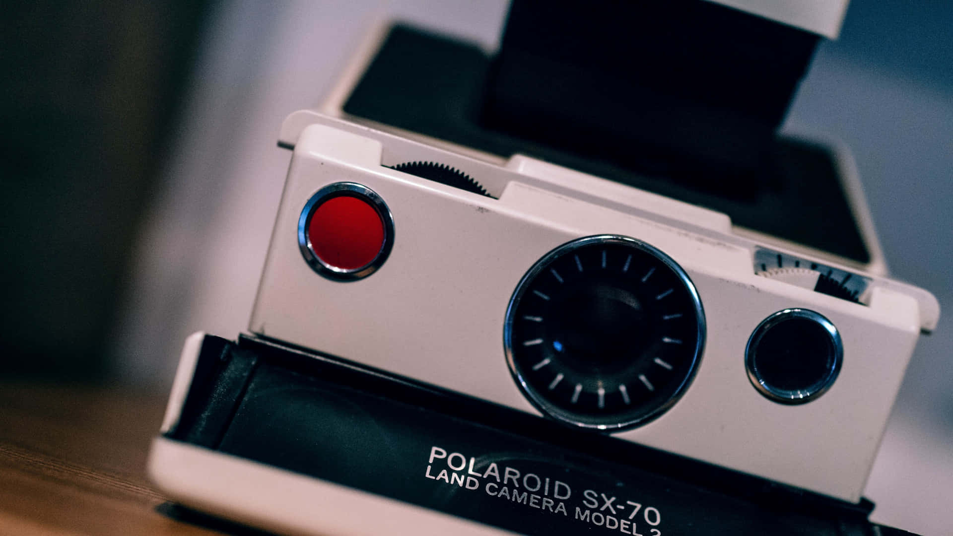 復古白色Polaroid SX-70相機，帶紅色快門按鈕和鉻色細節。