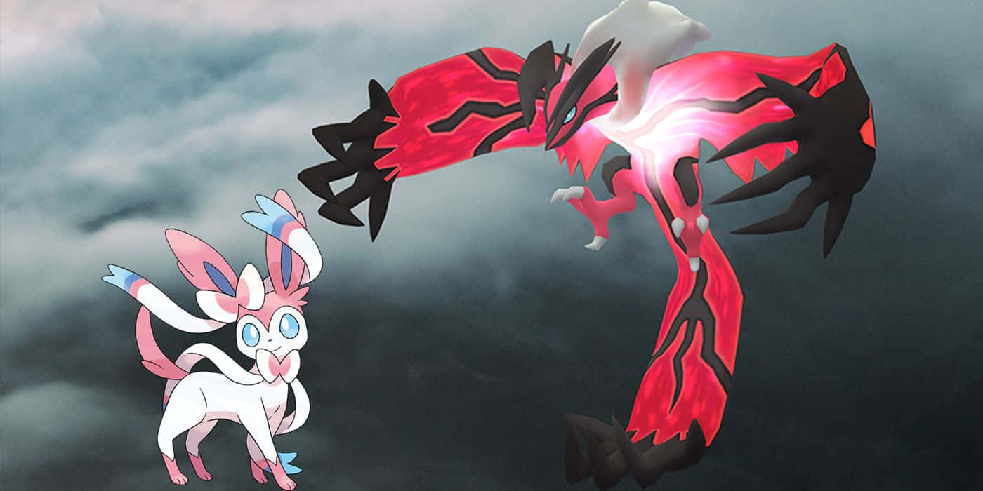寶可夢 Sylveon 與傳說寶可夢 Yveltal 壁紙 — 一隻粉紅色和白色的小精靈正面向一隻紅色和黑色的巨龍般精靈，背景是暴風雨的灰色天空。