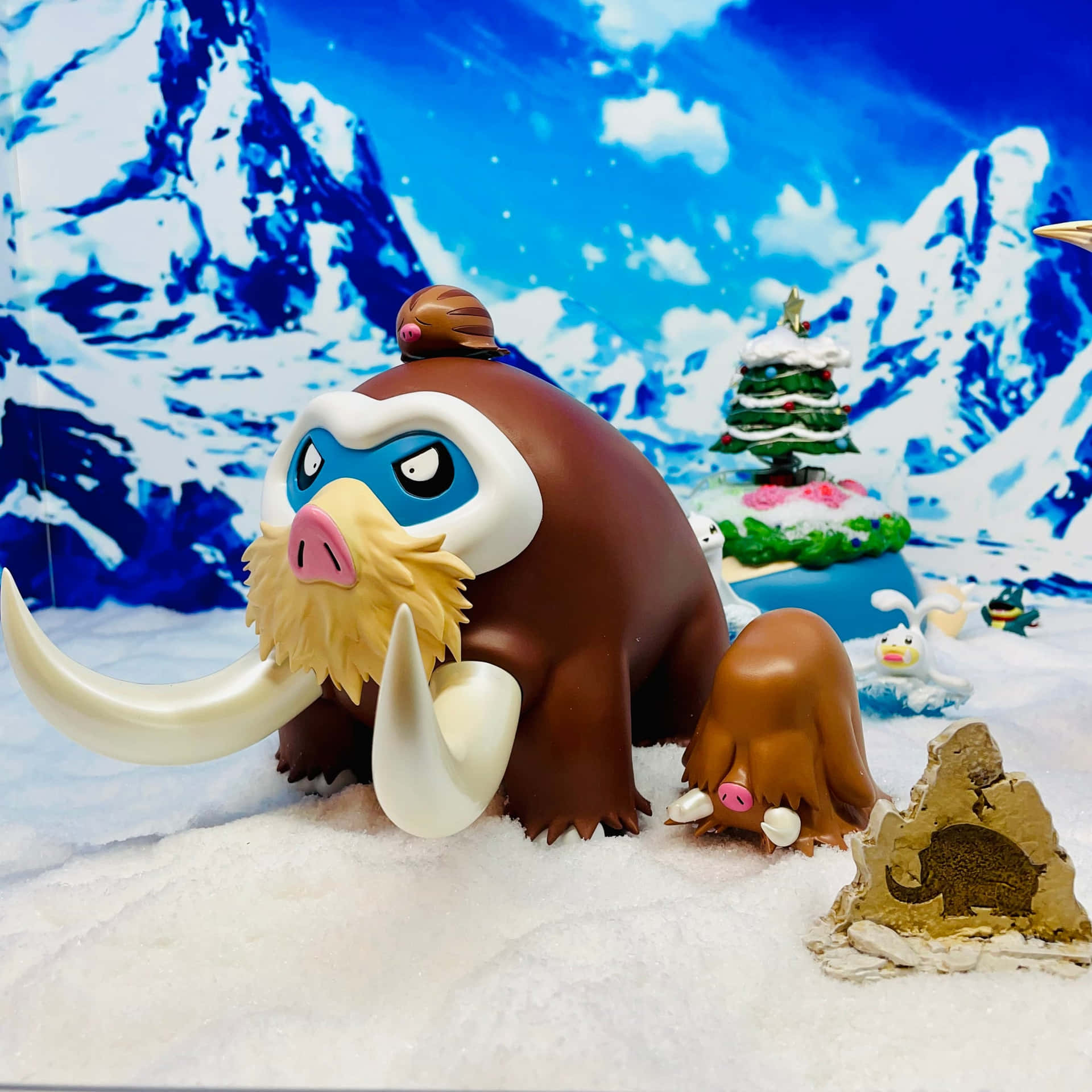 雪地場景中的長毛象玩具，有聖誕樹和其他小雕像。