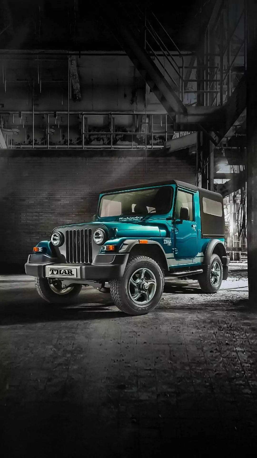 青綠色Mahindra Thar SUV在昏暗的工業倉庫中，帶有戲劇性的燈光。