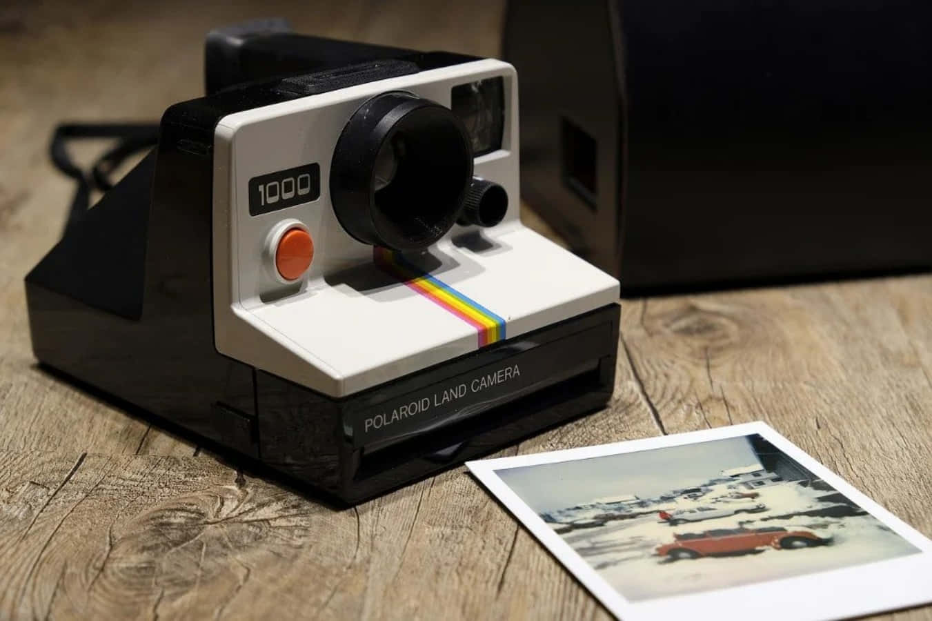 Polaroid相機，附有雪中汽車的即影即有照片，木質表面