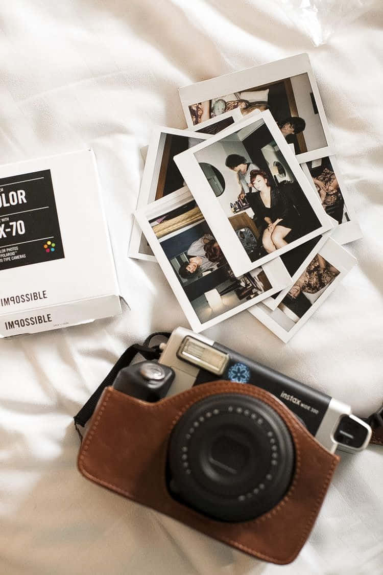 白色床罩上的Instax相機和即影即有照片。 — 寶麗來 GIF 壁紙