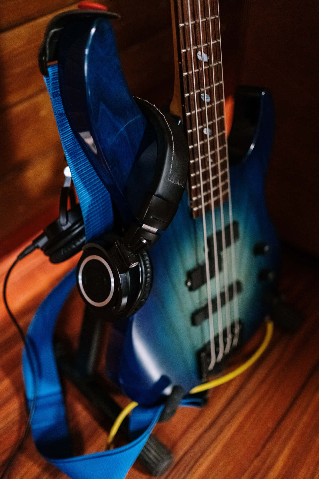 藍色低音結他，耳機掛在琴頸上，置於木地板。