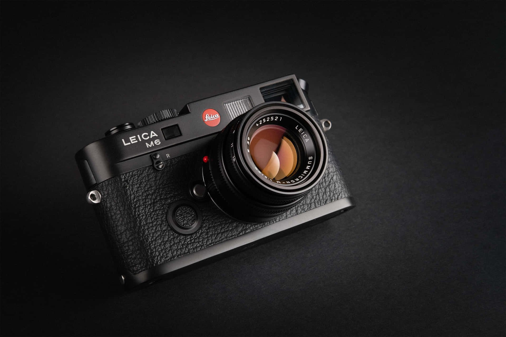 黑色 Leica M6 菲林相機在深色背景上，帶有鏡頭反射。