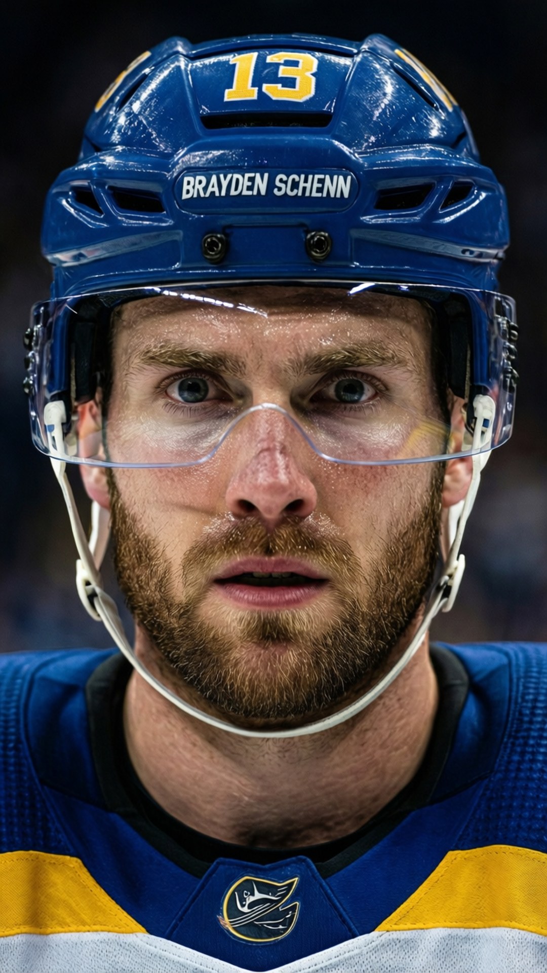 專注凝視 壁紙 — 冰球運動員 Brayden Schenn 身穿藍色和金色裝備，在透明面罩後露出專注而銳利的眼神特寫。