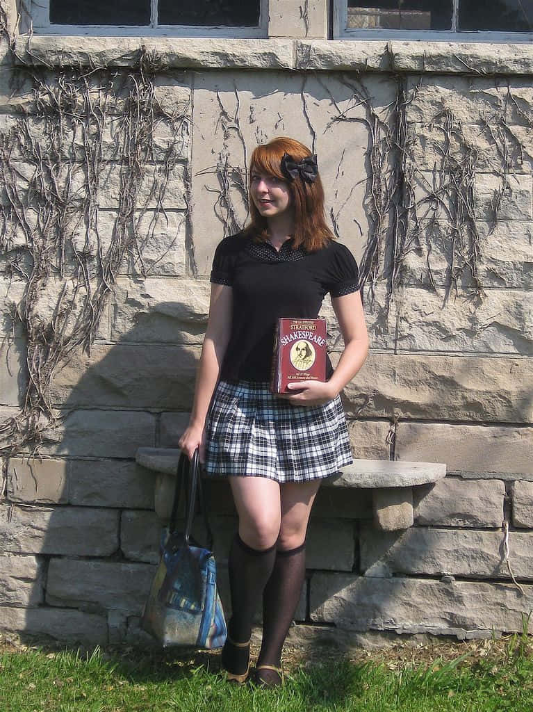 年輕女性在長滿常春藤的石牆旁拿著莎士比亞的書