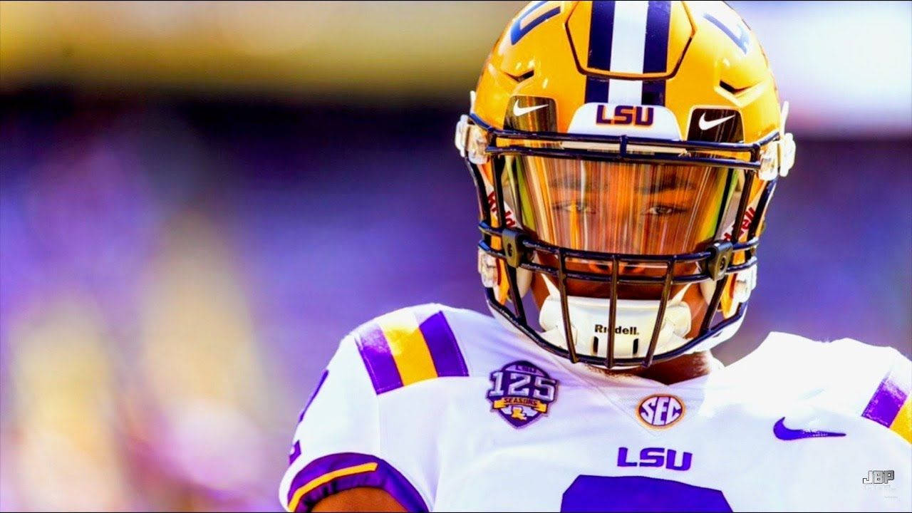 Justin Jefferson LSU 壁紙 — 專注的LSU足球員近距離特寫，身穿黃色頭盔和帶有紫色點綴的白色球衣。