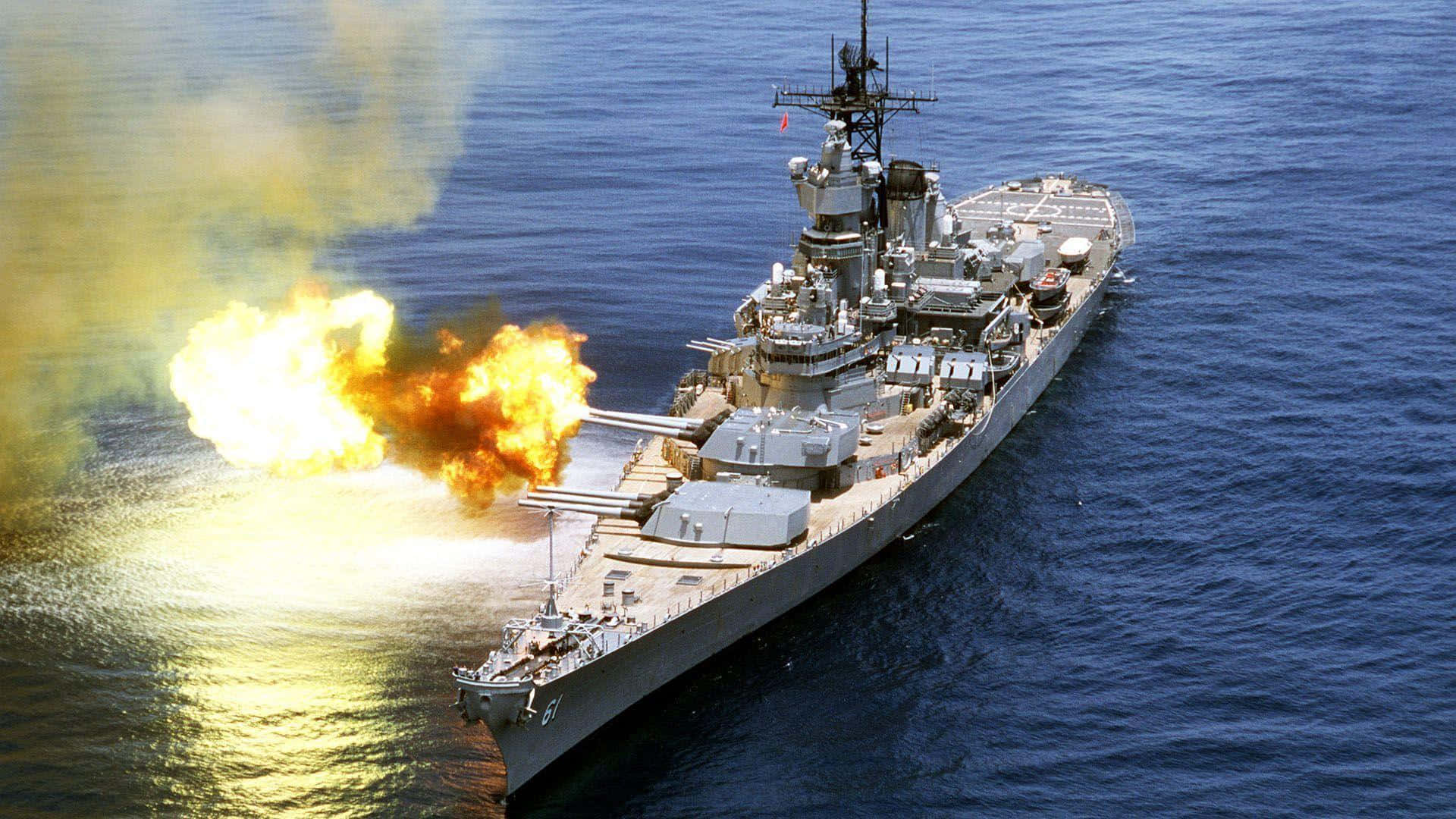 尊貴的海軍力量 壁紙 — 一艘戰艦在深藍色海洋上發射巨型火炮，產生明亮的橙色爆炸和黃色煙霧。