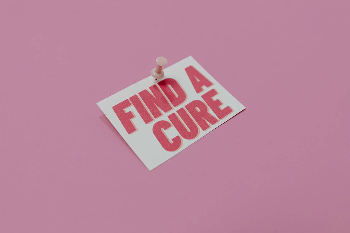 一張粉紅色卡片，上面釘有訊息「Find a Cure」，背景為粉紅色。