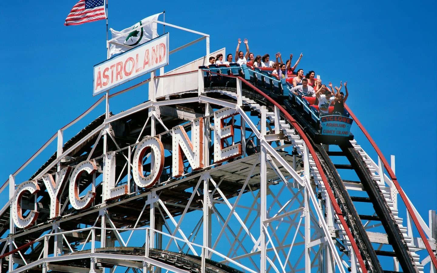 Roller Coaster 桌布 壁紙 — 尋求刺激的人在晴朗的藍天下，登上阿斯楚蘭德高聳的旋風過山車頂峰，興奮地尖叫。