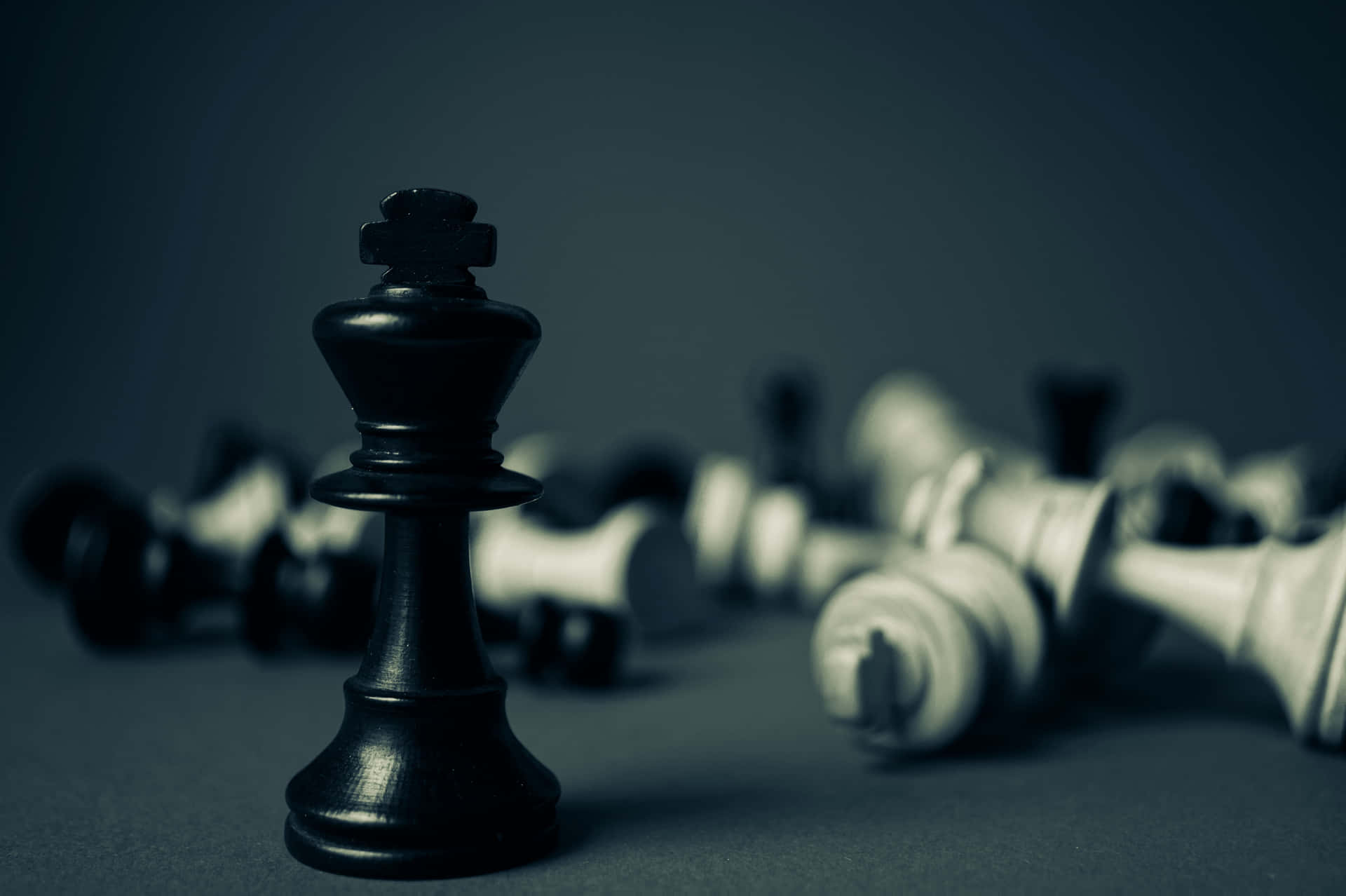 一個站立的黑色國際象棋國王，身後有倒下的白色棋子。