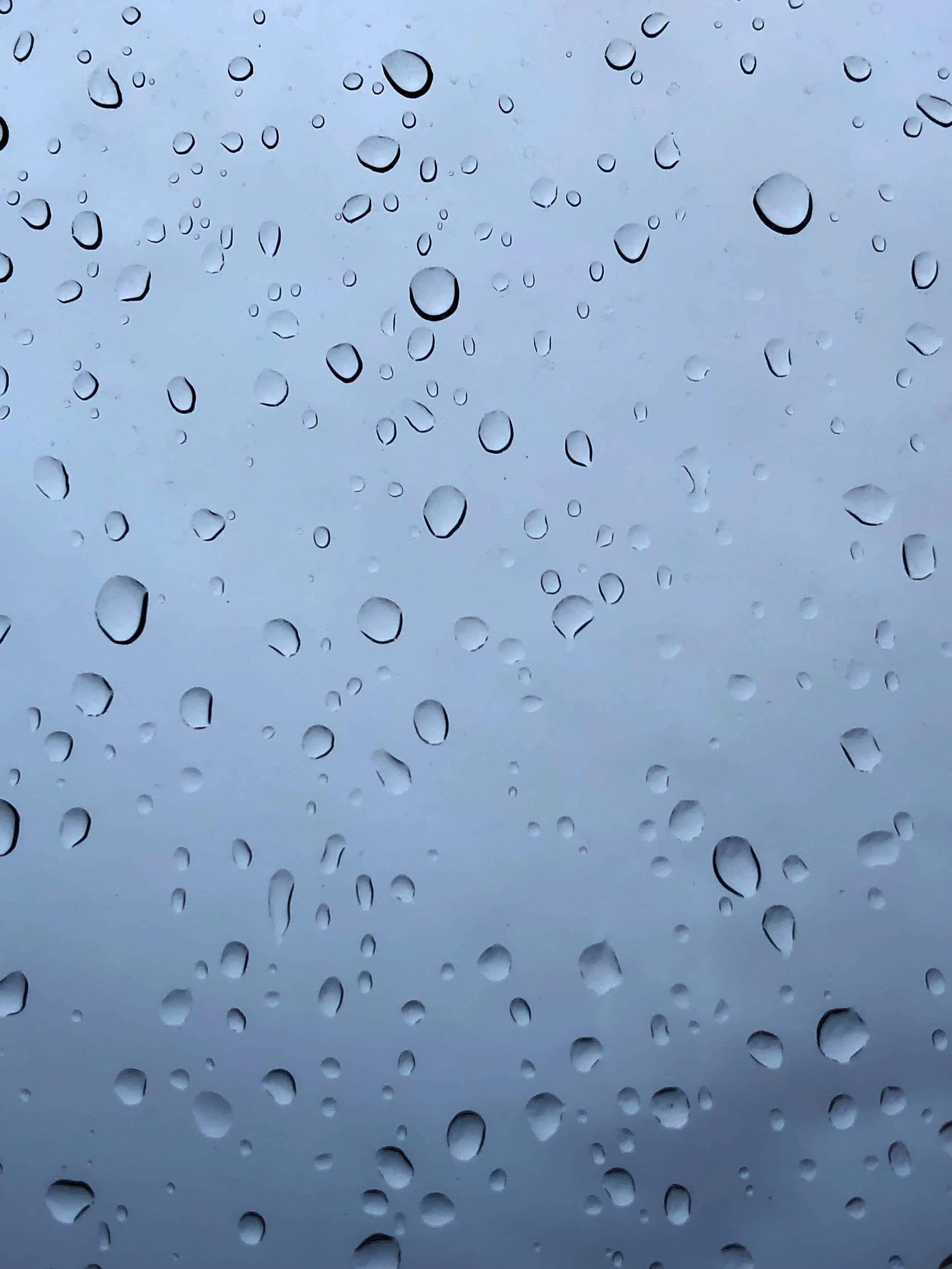 對稱的完美典範——一滴水珠 壁紙 — 雨滴依附在玻璃表面，顯露出背後柔和的灰色天空。
