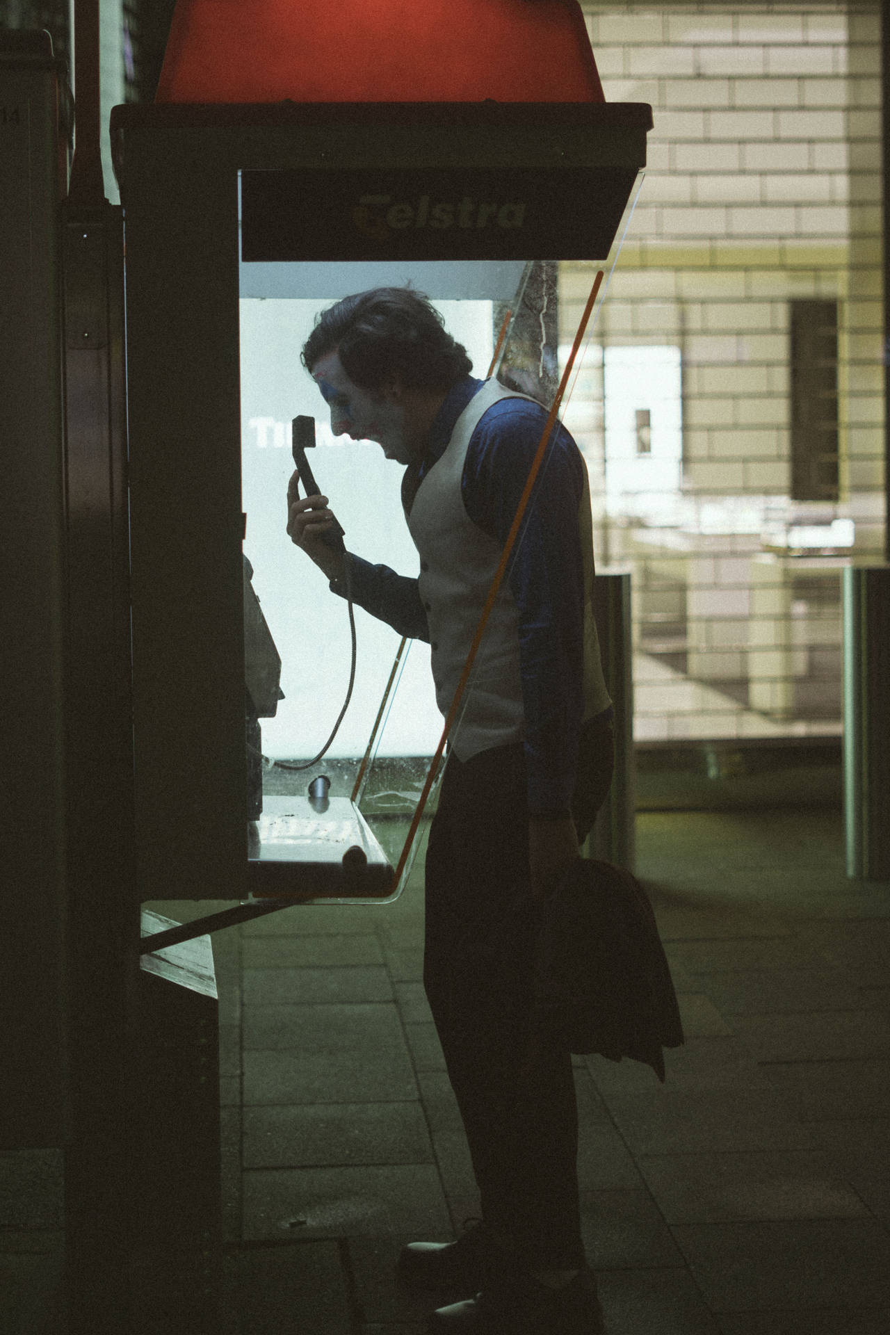 男子在夜間於城市環境中使用復古紅色電話亭。