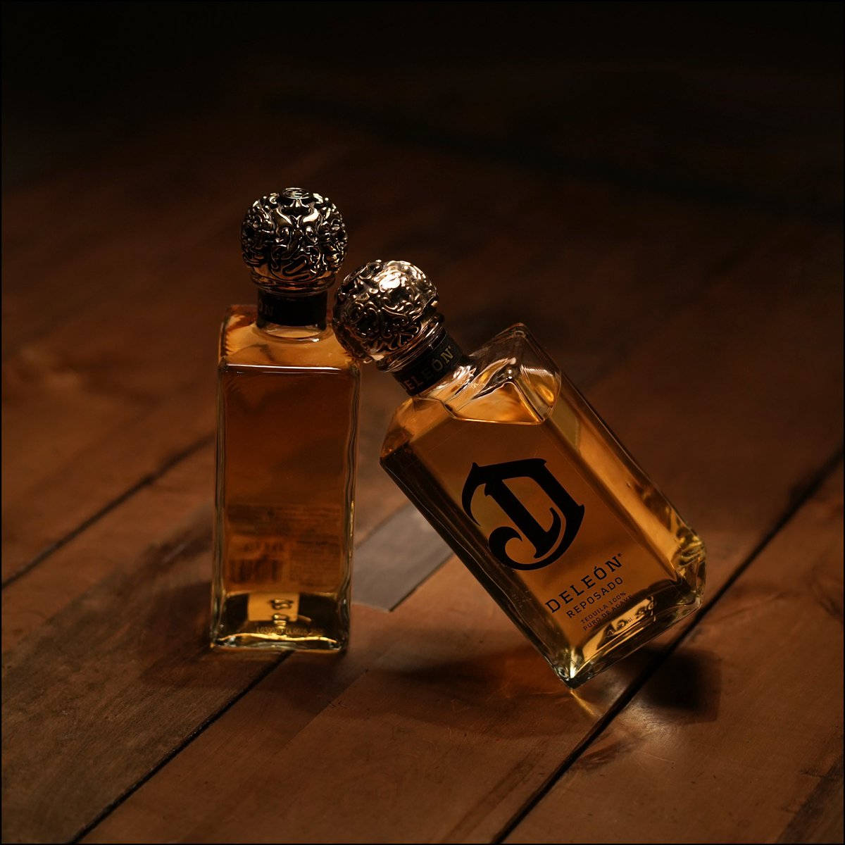 兩瓶DeLeón龍舌蘭酒在溫暖燈光下的木桌上