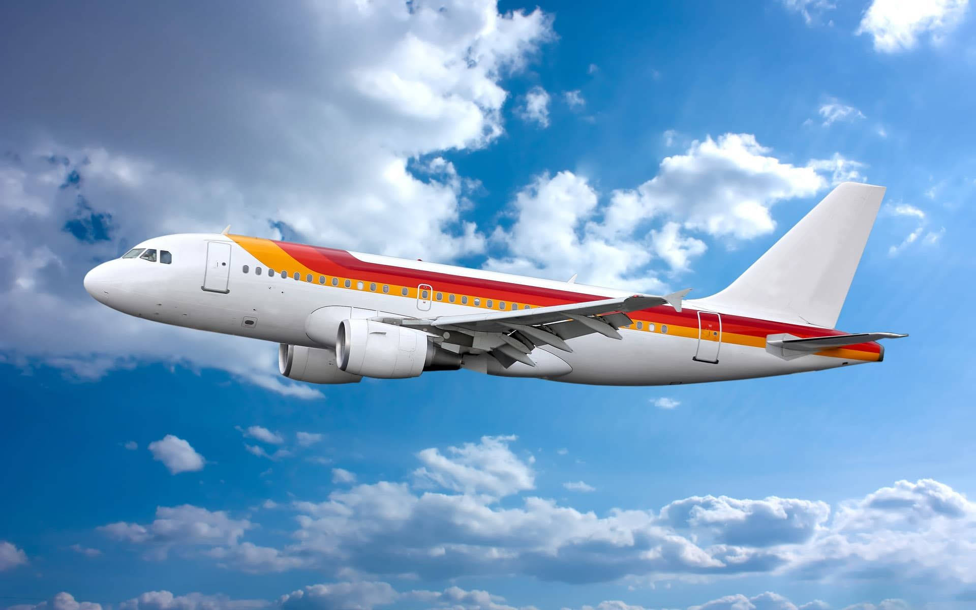 小型飛機在絢麗天空中攀升 壁紙 — 一架帶有紅色和橙色條紋的白色客機在點綴著蓬鬆白雲的明亮藍天中翱翔。