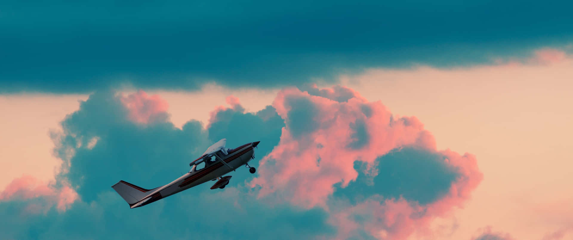 小型飛機飛過色彩繽紛的日落雲層。