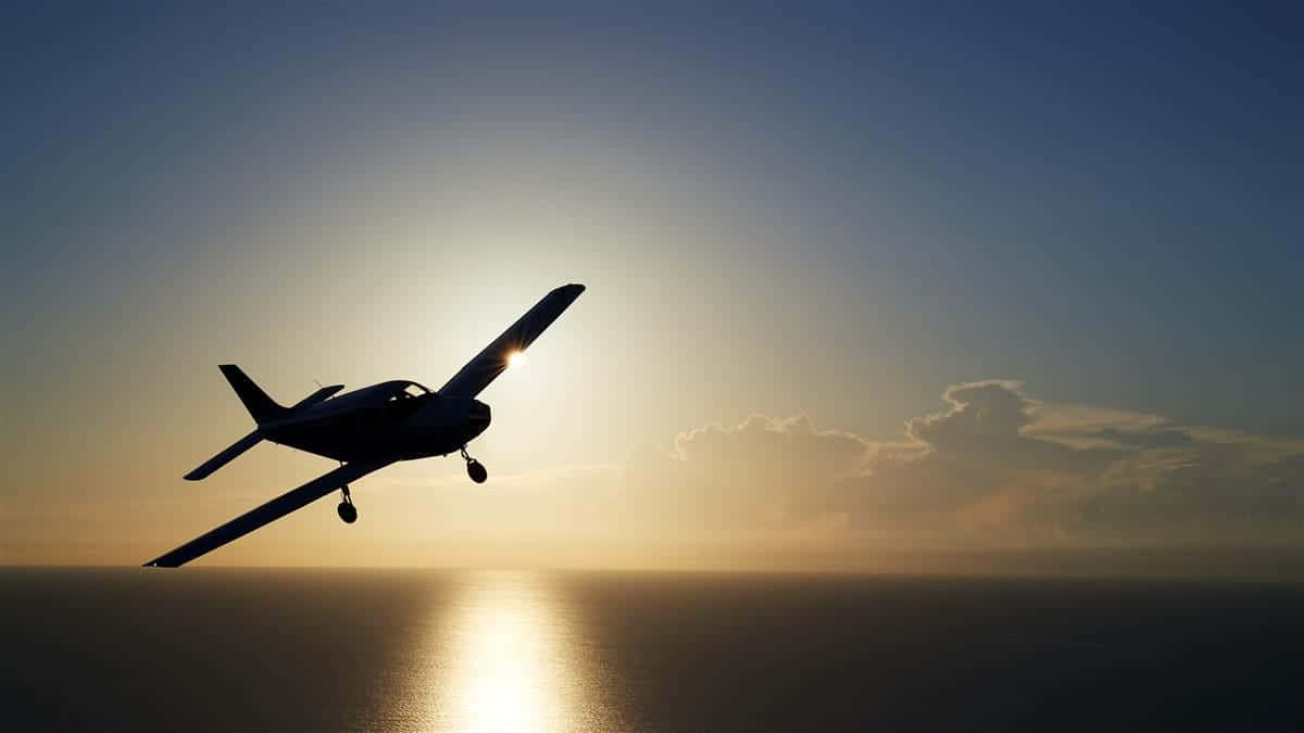 夕陽下小型飛機飛越海洋的剪影。