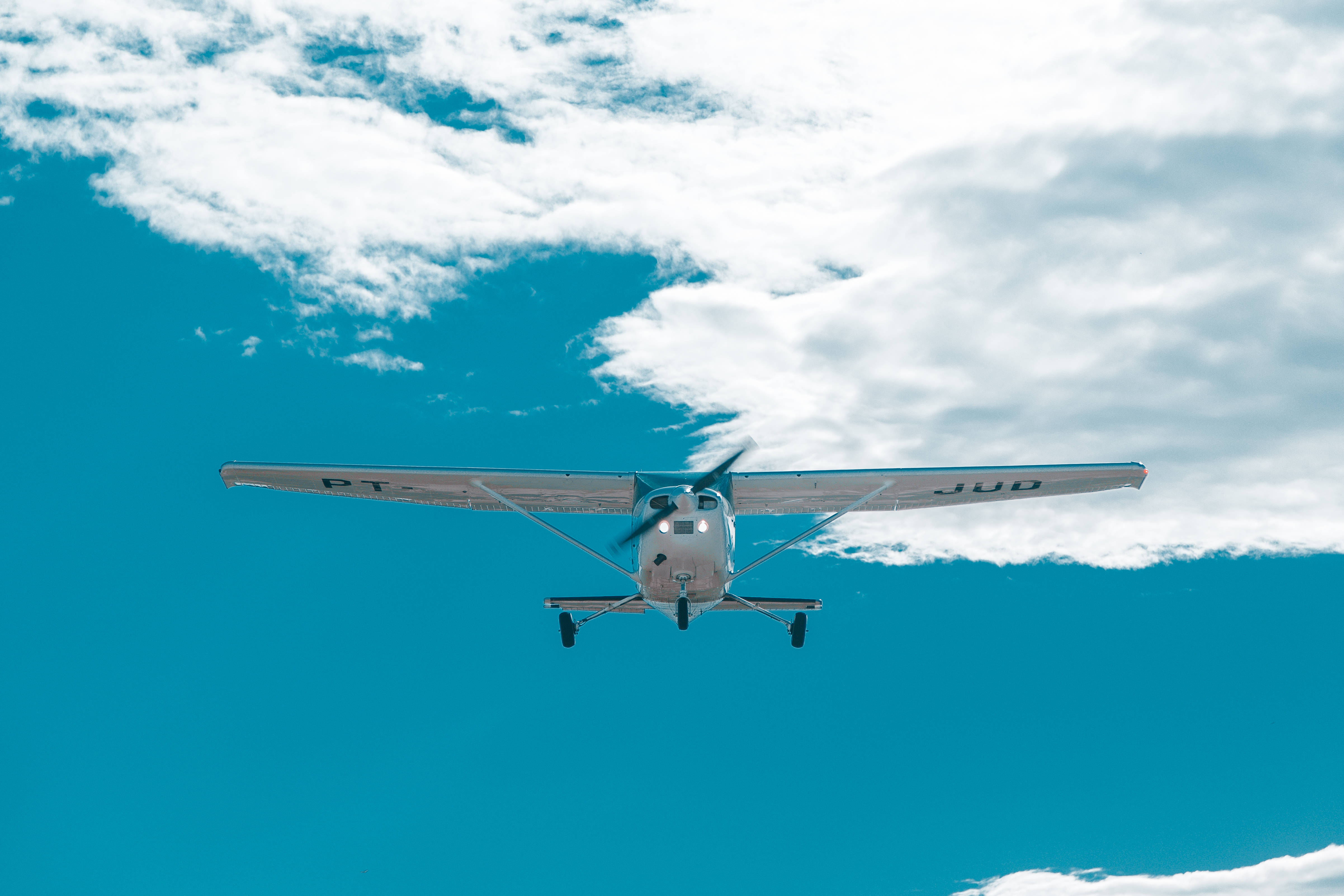 小型飛機飛越藍天白雲 壁紙 — 一架白色小飛機正面飛向一片點綴著蓬鬆白雲的鮮豔藍天。