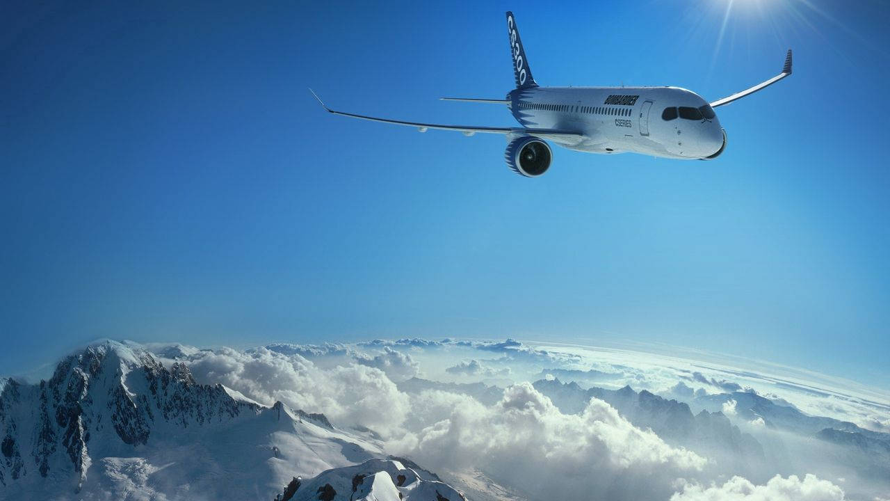 小型飛機飛越雪地 壁紙 — 一架白色飛機在晴朗藍天和陽光照射下，翱翔於積雪的山峰和蓬鬆的白雲之上。