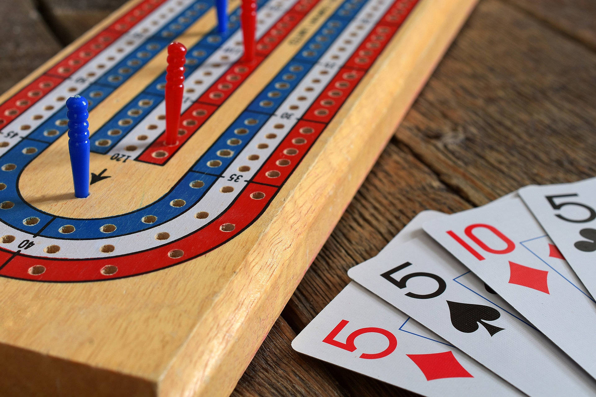 木質表面上帶有釘子和撲克牌的克里比奇棋盤。