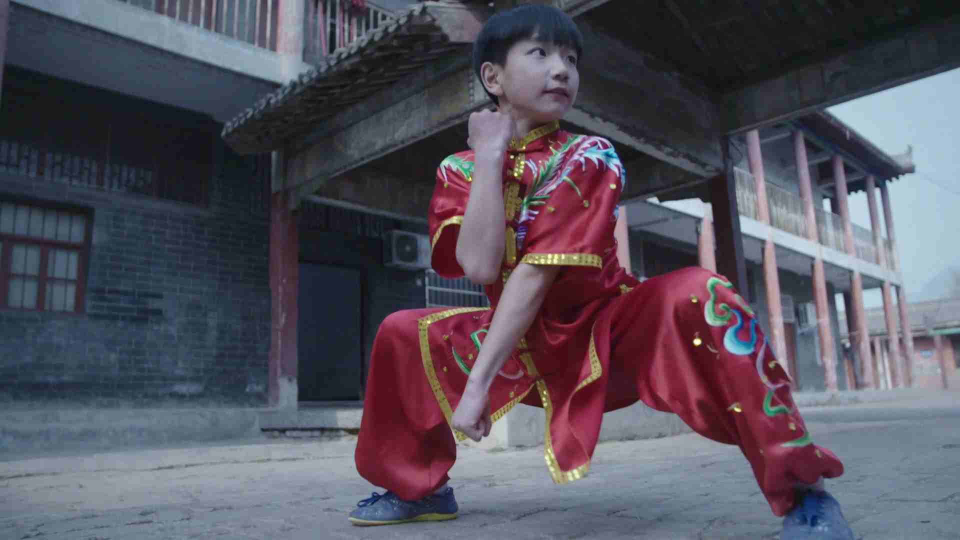 穿著紅色武術服的小孩在庭院練習姿勢