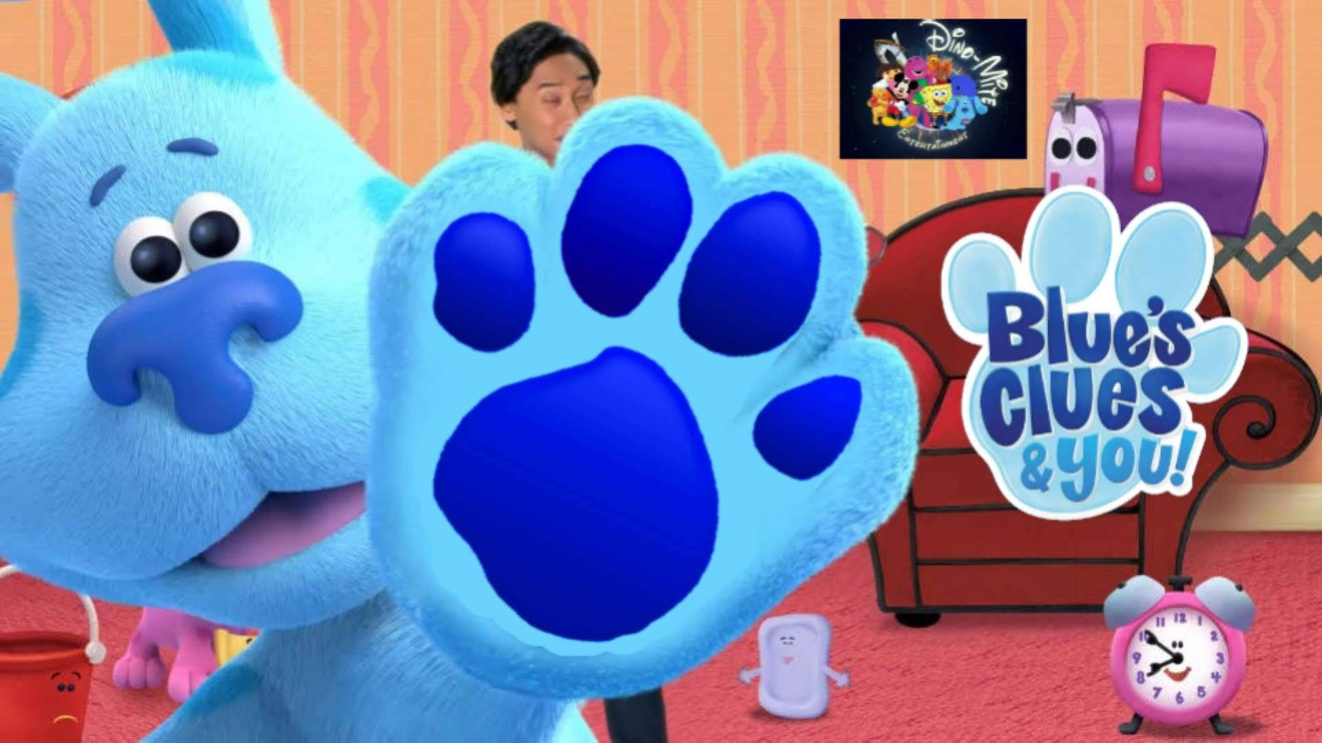 小狗Blue的爪印 壁紙 — 一隻快樂的藍色狗，帶有巨大的爪印，在色彩繽紛的兒童節目場景中揮手，場景中有玩具和紅色沙發。