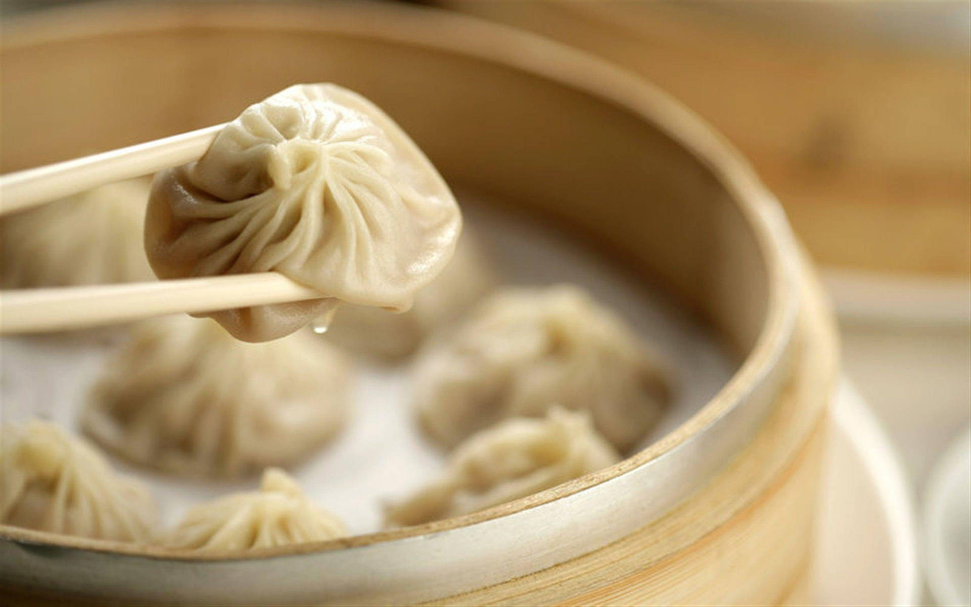 筷子從竹蒸籠中夾起一個冒煙的餃子。