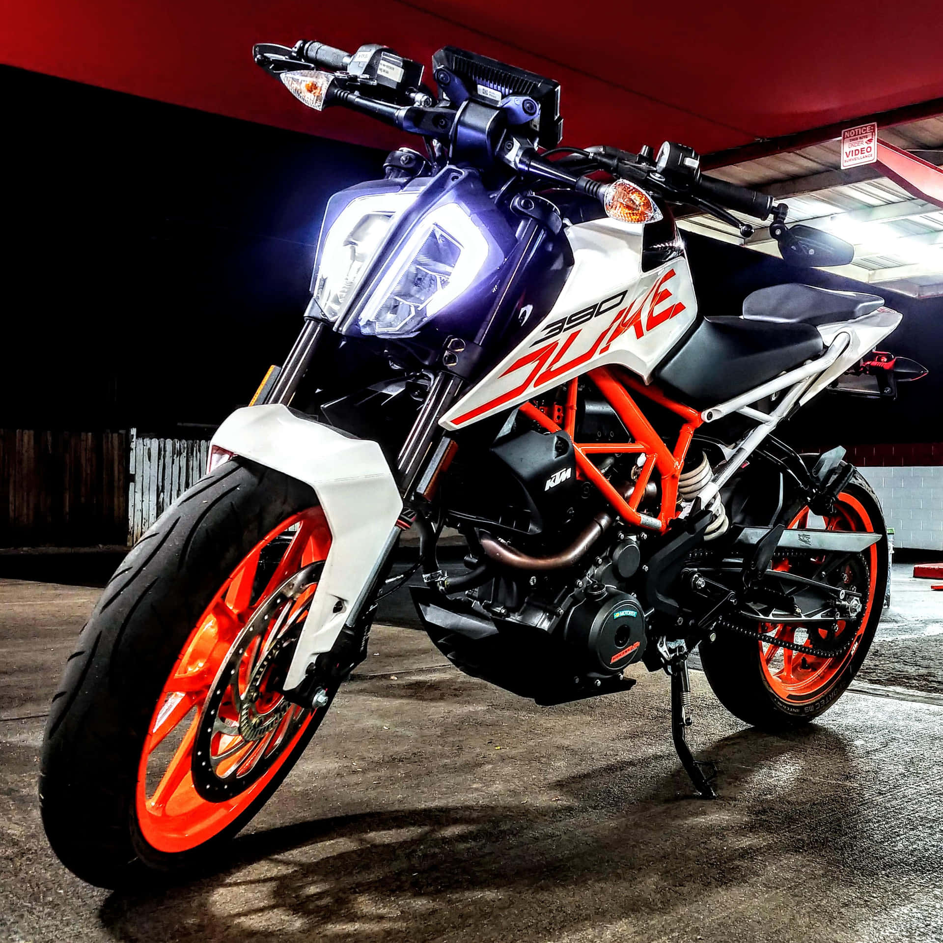 一輛帶有橙色車輪和白色車身的KTM 390 Duke電單車停在車庫中。