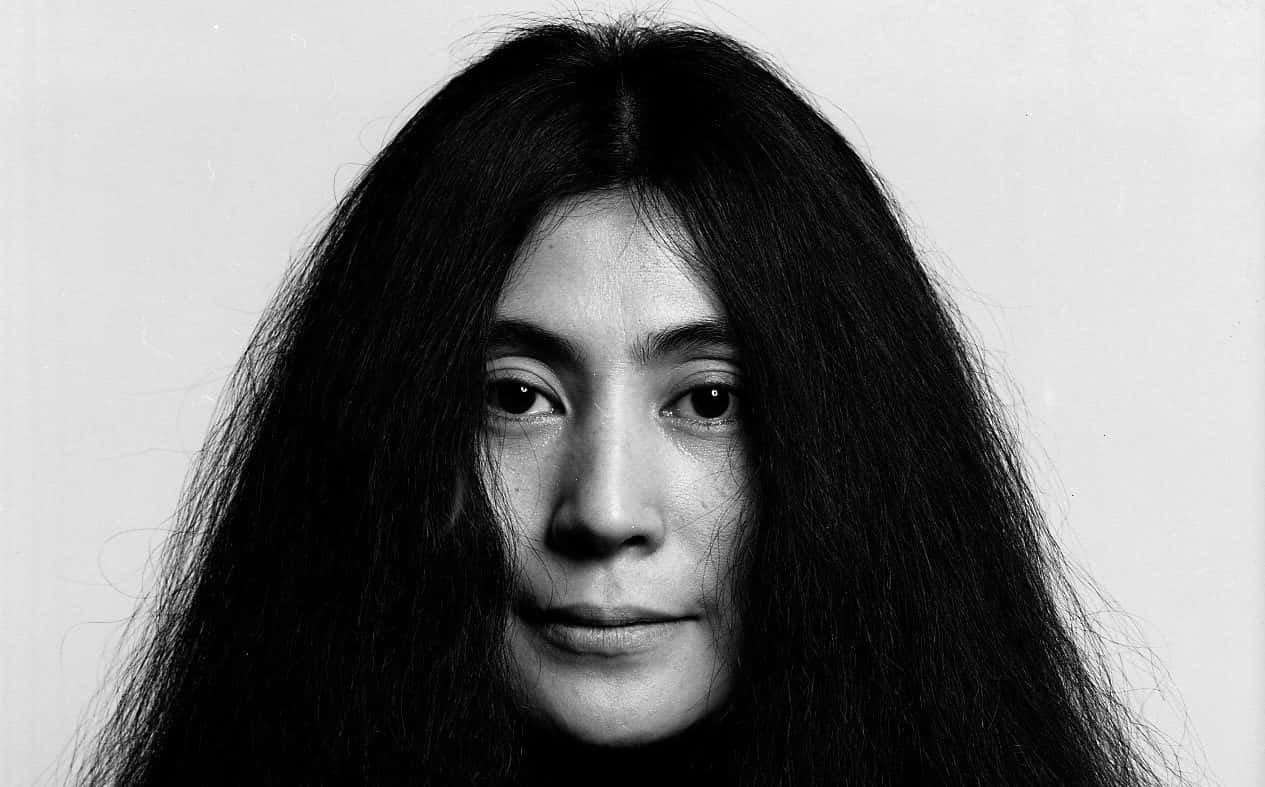 長黑髮女性的黑白特寫肖像，注視著觀看者。