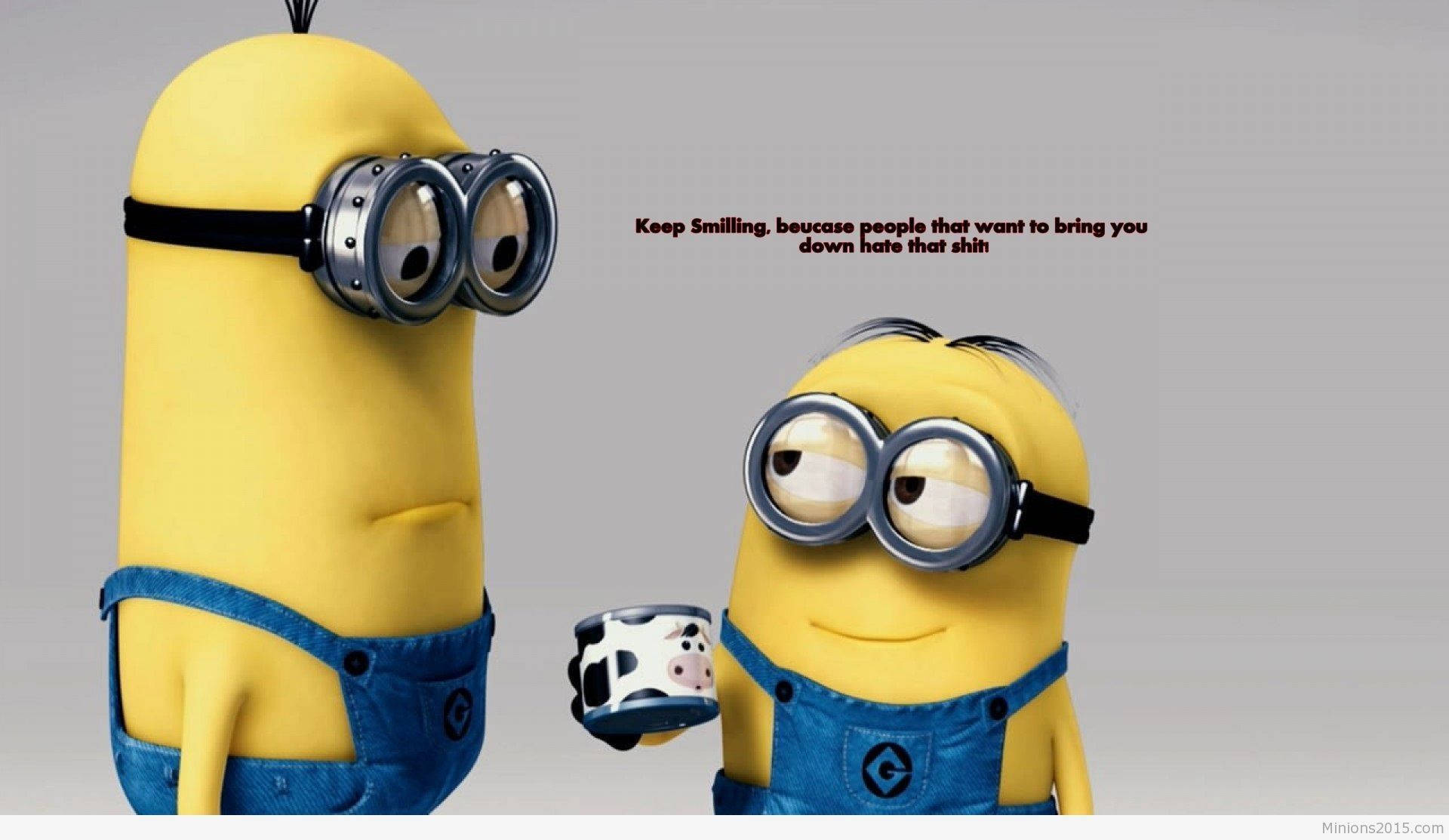 小黃人對話搞笑卡通 壁紙 — 兩個穿著藍色工裝褲的黃色Minions在純灰色背景前開心微笑，其中一個拿著一個乳牛圖案的杯子。