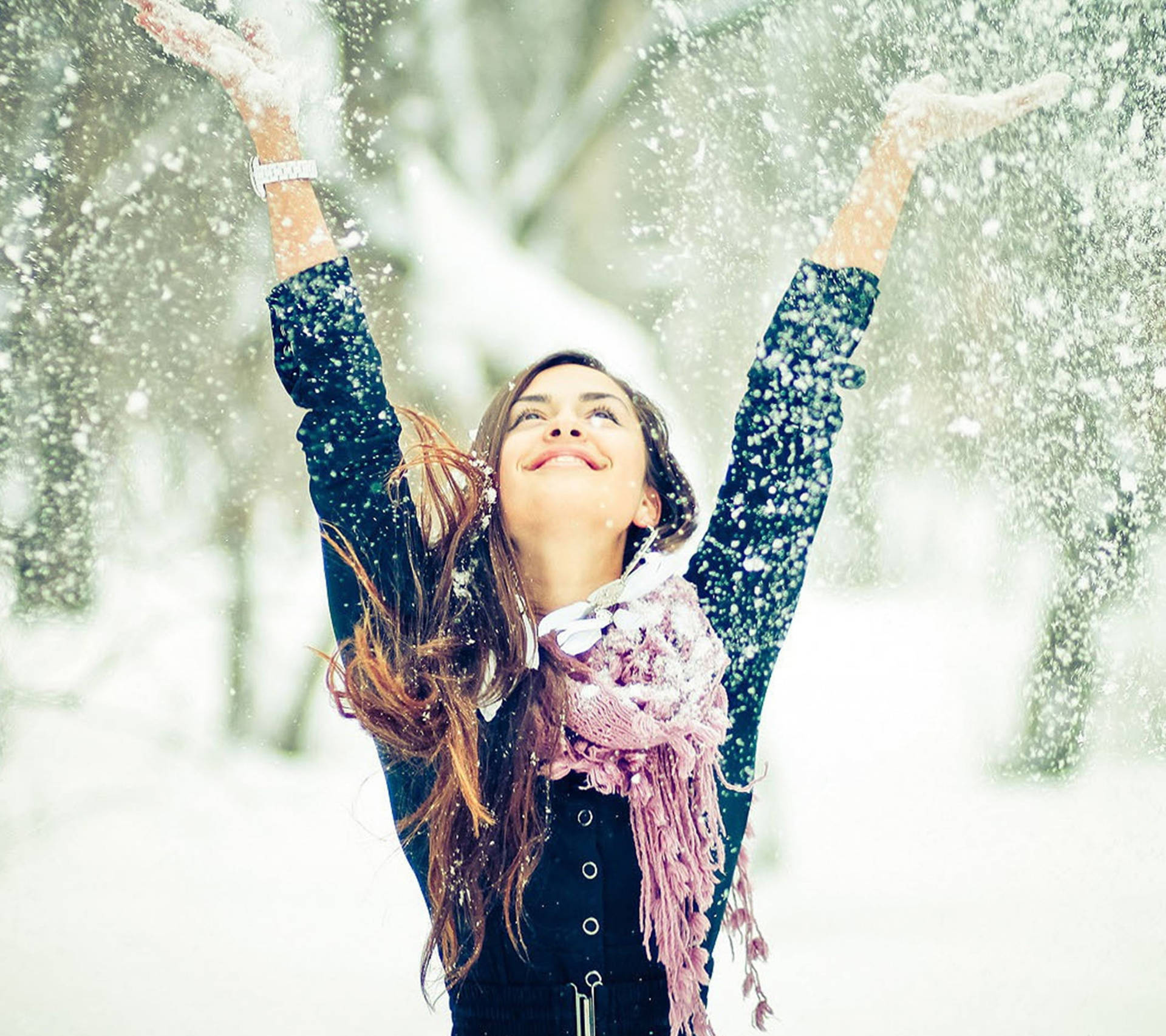 女性在冬季森林中舉起雙臂拋雪。