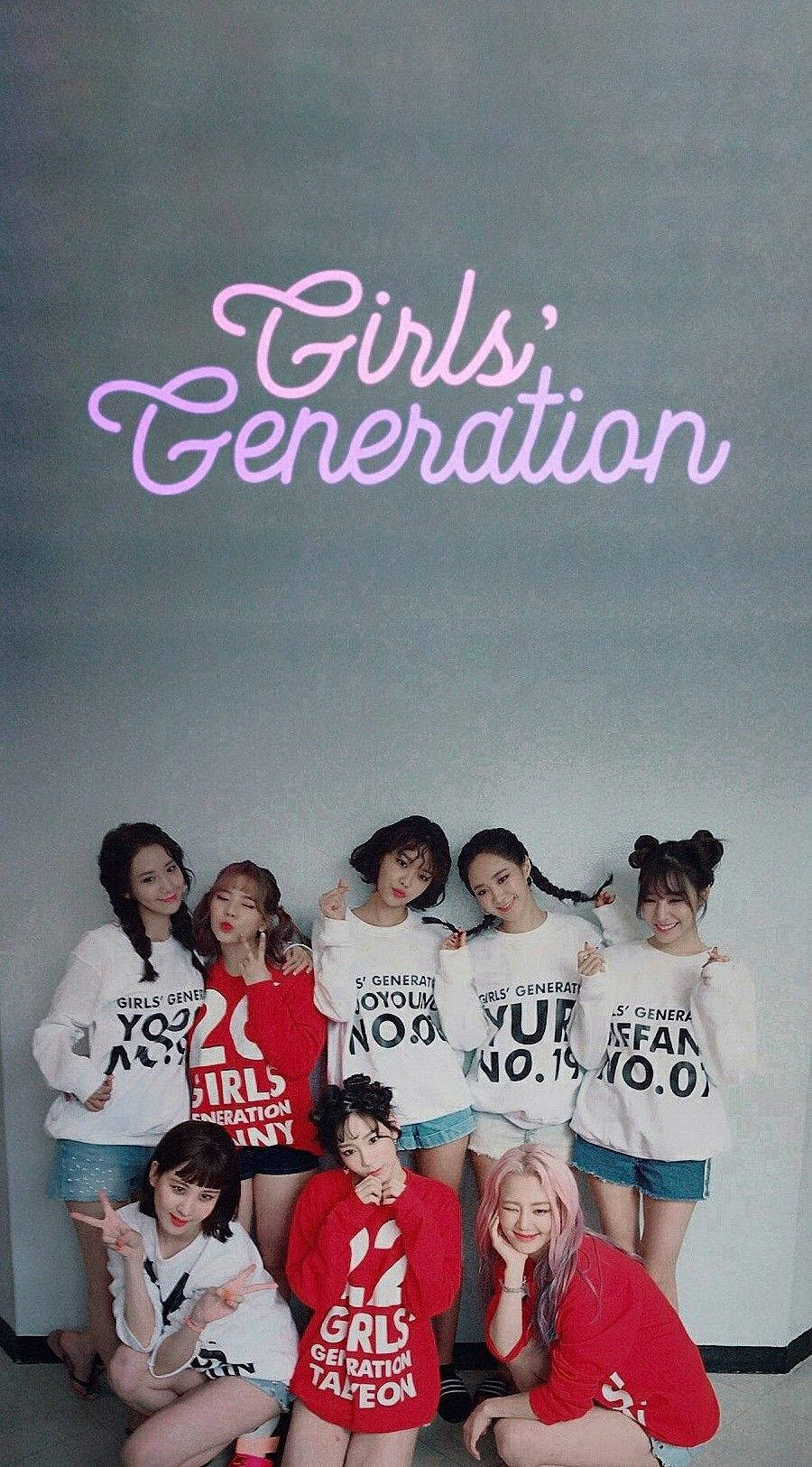 七個K-pop女孩穿著相配的T恤，在發光的霓虹燈招牌下擺姿勢。