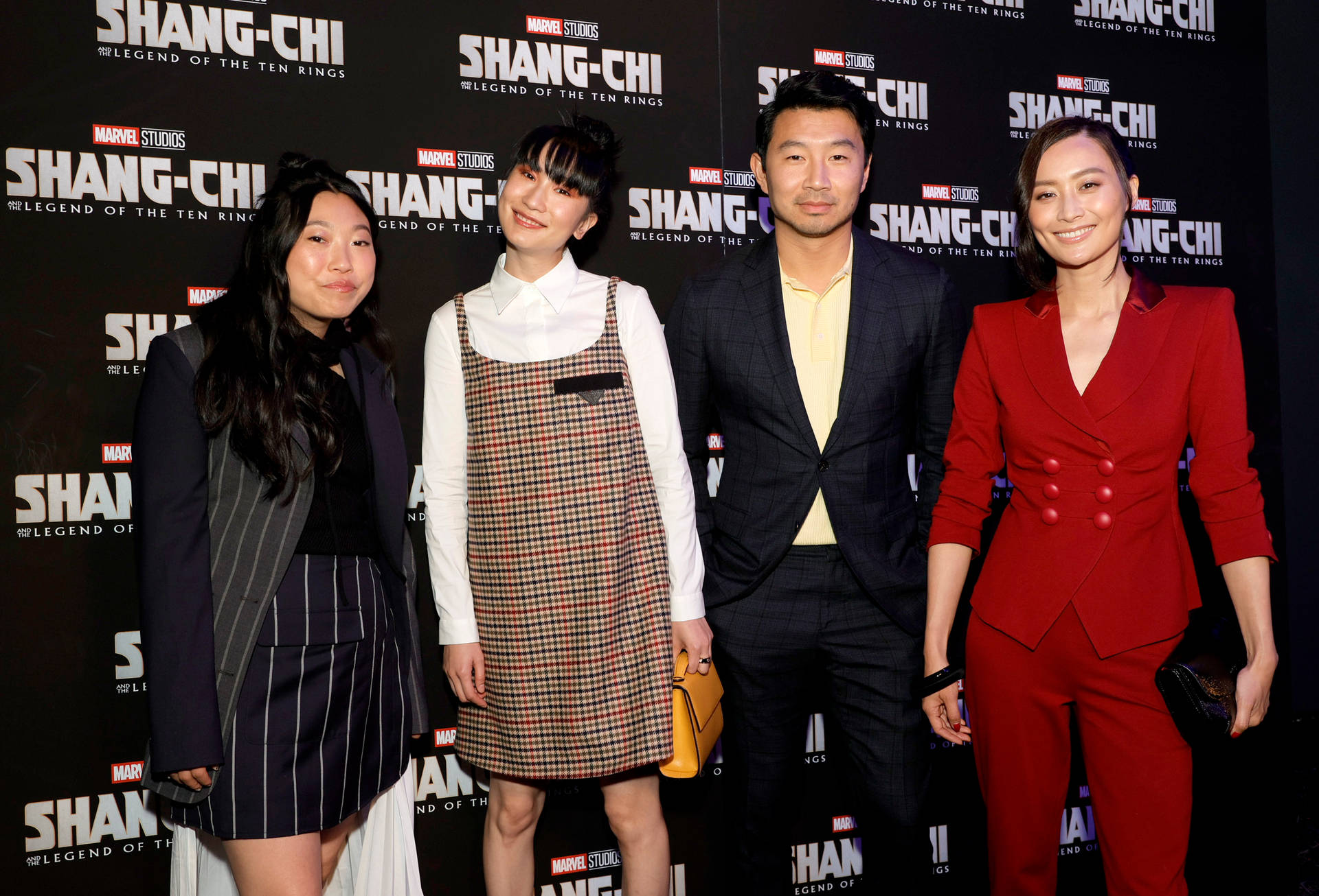 四位微笑的人們在Shang-Chi電影首映活動中穿著正式服裝。