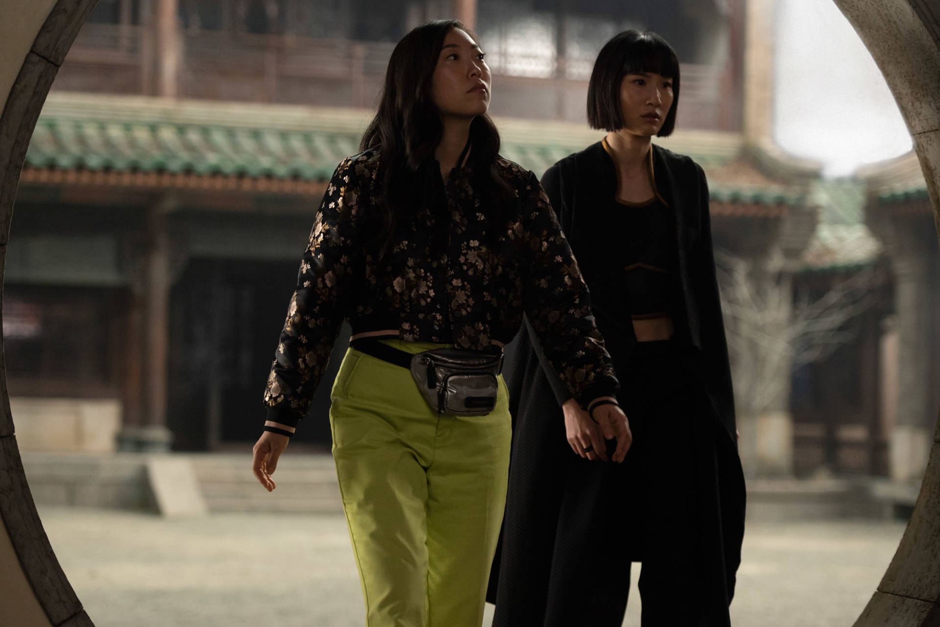 兩位女士在傳統庭院中穿過一個石拱門。