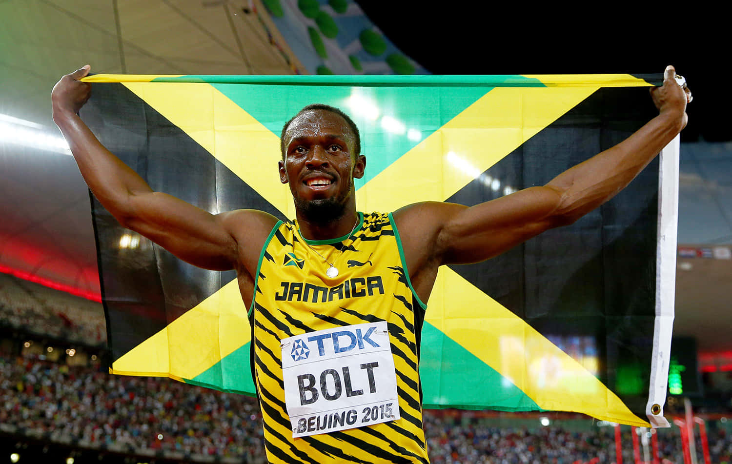 Usain Bolt 喺北京2015年田徑賽事中，手持牙買加國旗慶祝勝利。