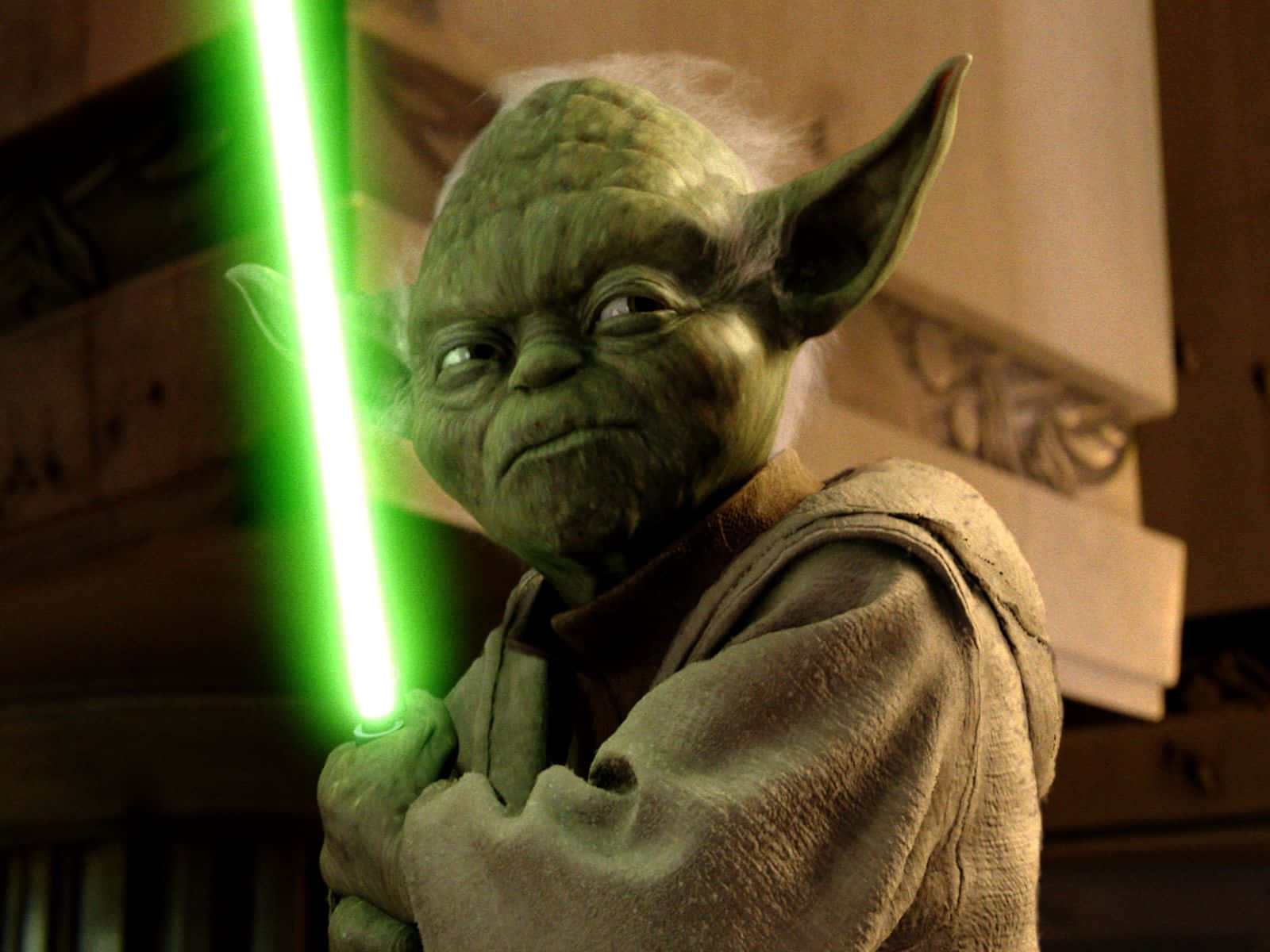 Yoda 桌布 壁紙 — 尤達在昏暗的室內手持發光的綠色光劍，表情嚴肅。