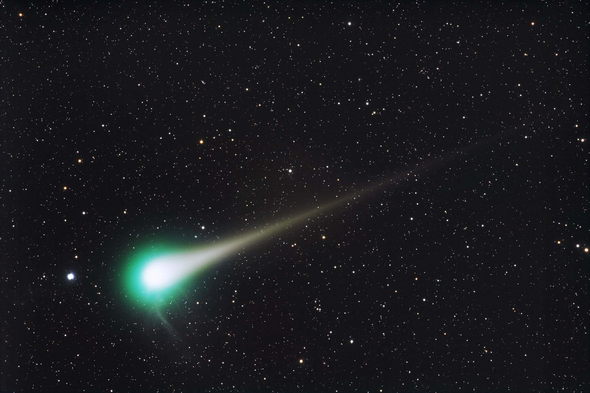 尼斯的晶瑩海景 壁紙 — 一顆發光的綠色彗星劃過滿天星斗的夜空，留下一條發光的尾巴。