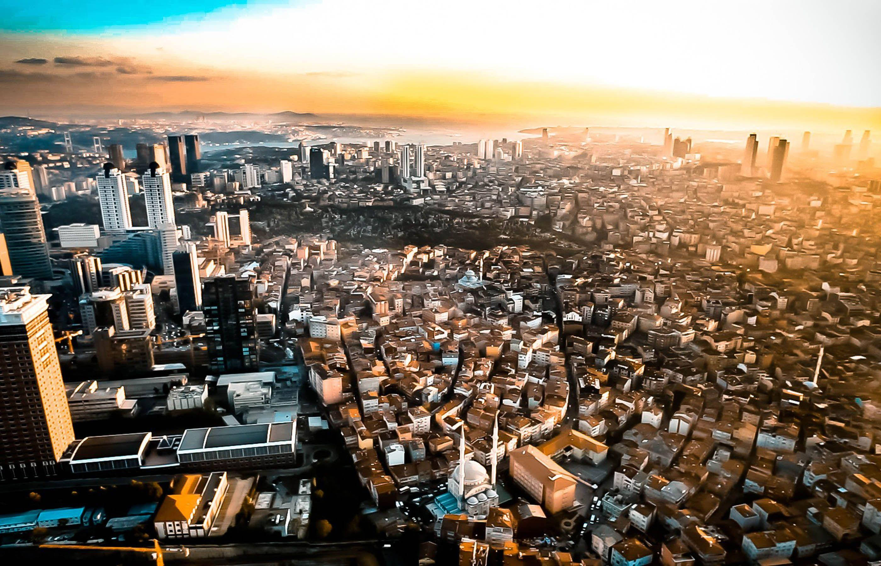 尼日利亞鄉村與城市景觀 壁紙 — 日落時分廣闊城市的鳥瞰圖，金色陽光灑滿現代摩天大樓和密集住宅區。