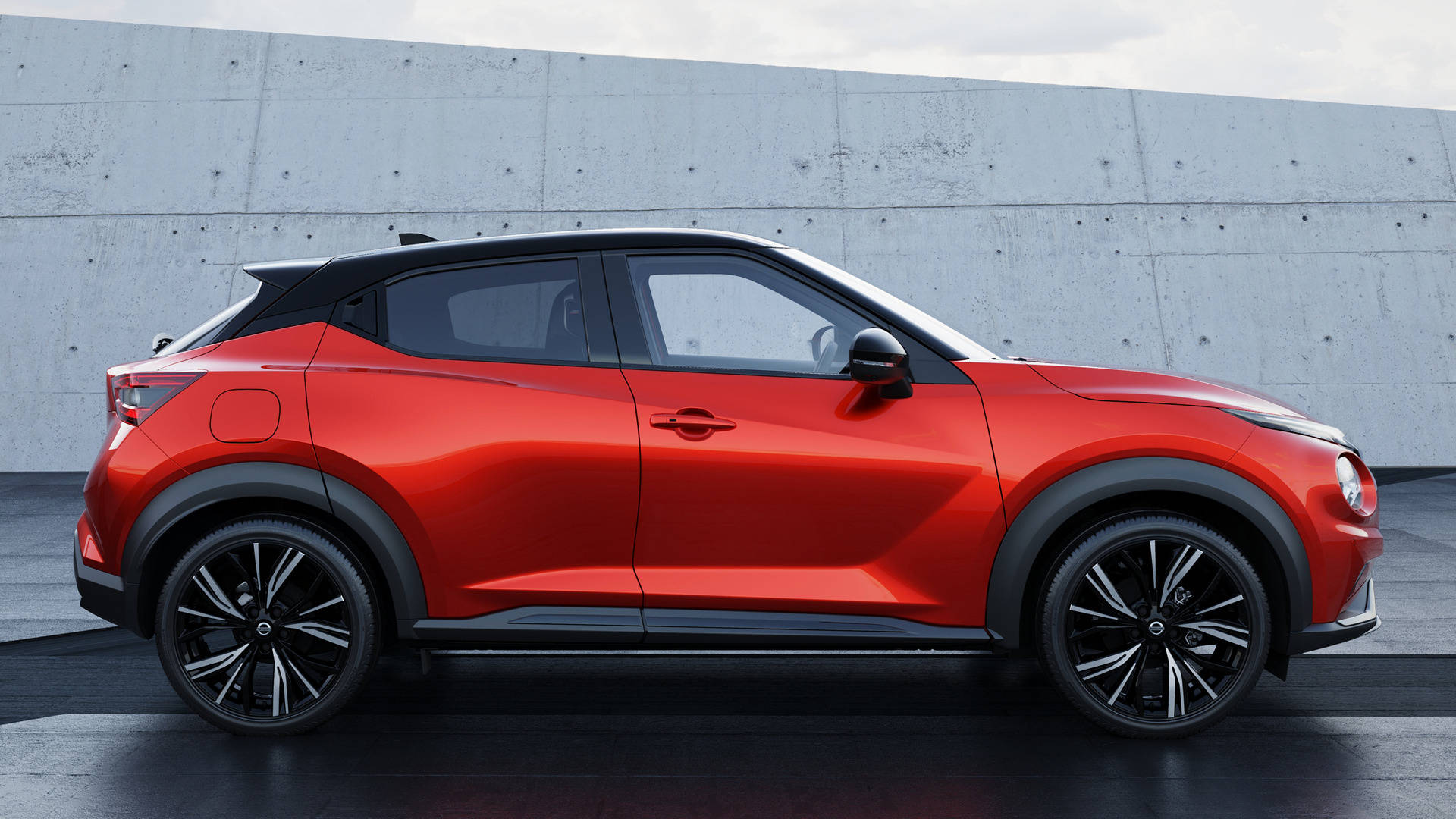 尼桑GTR Juke小型SUV 壁紙 — 一輛鮮紅色緊湊型SUV帶有黑色飾邊，在明亮日光下以側面輪廓矗立於簡約混凝土牆前。
