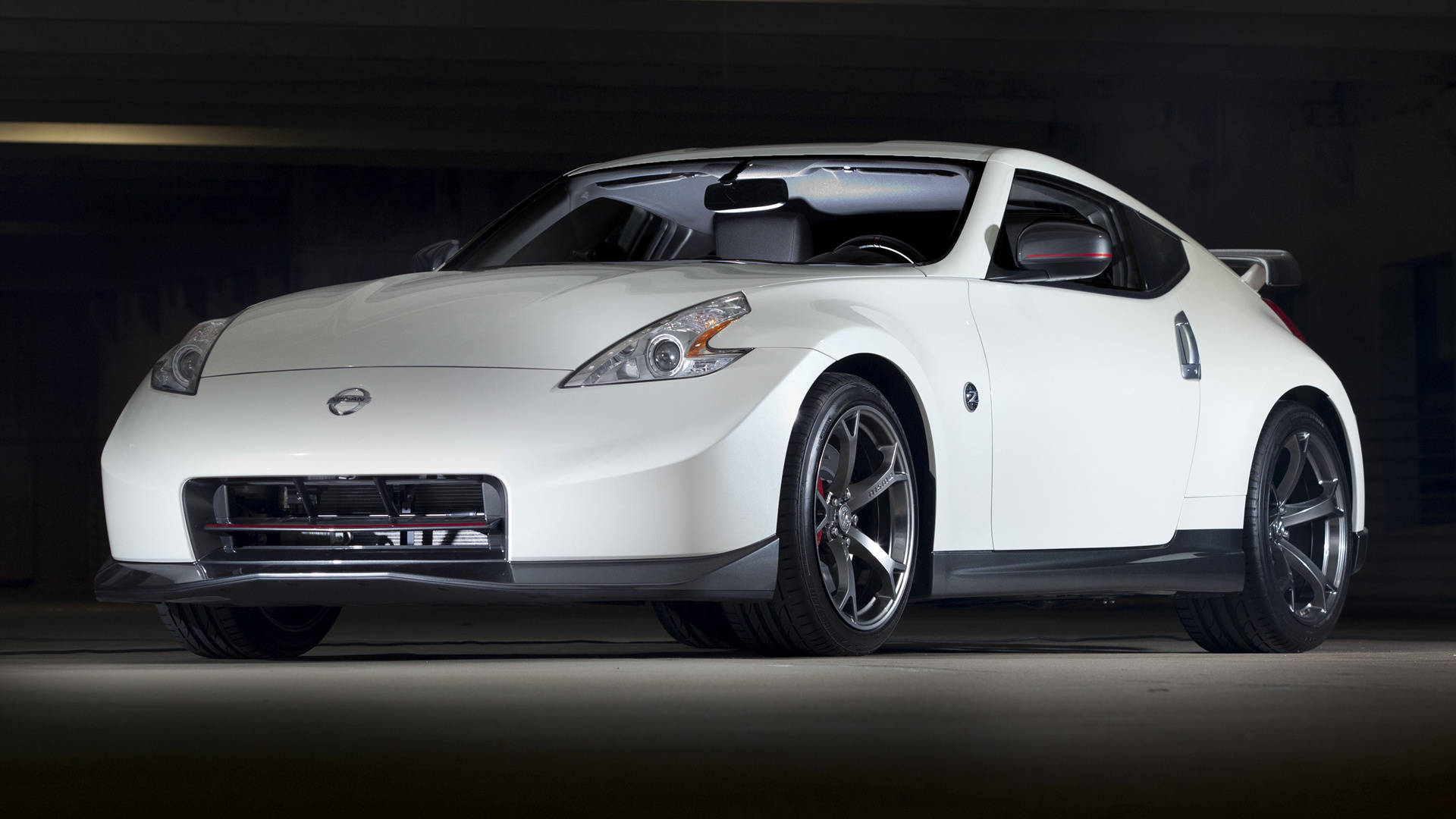 尼桑GTR Nismo車型 壁紙 — 一輛時尚的白色日產370Z跑車配黑色輪圈，停泊在混凝土車庫的昏暗燈光下。