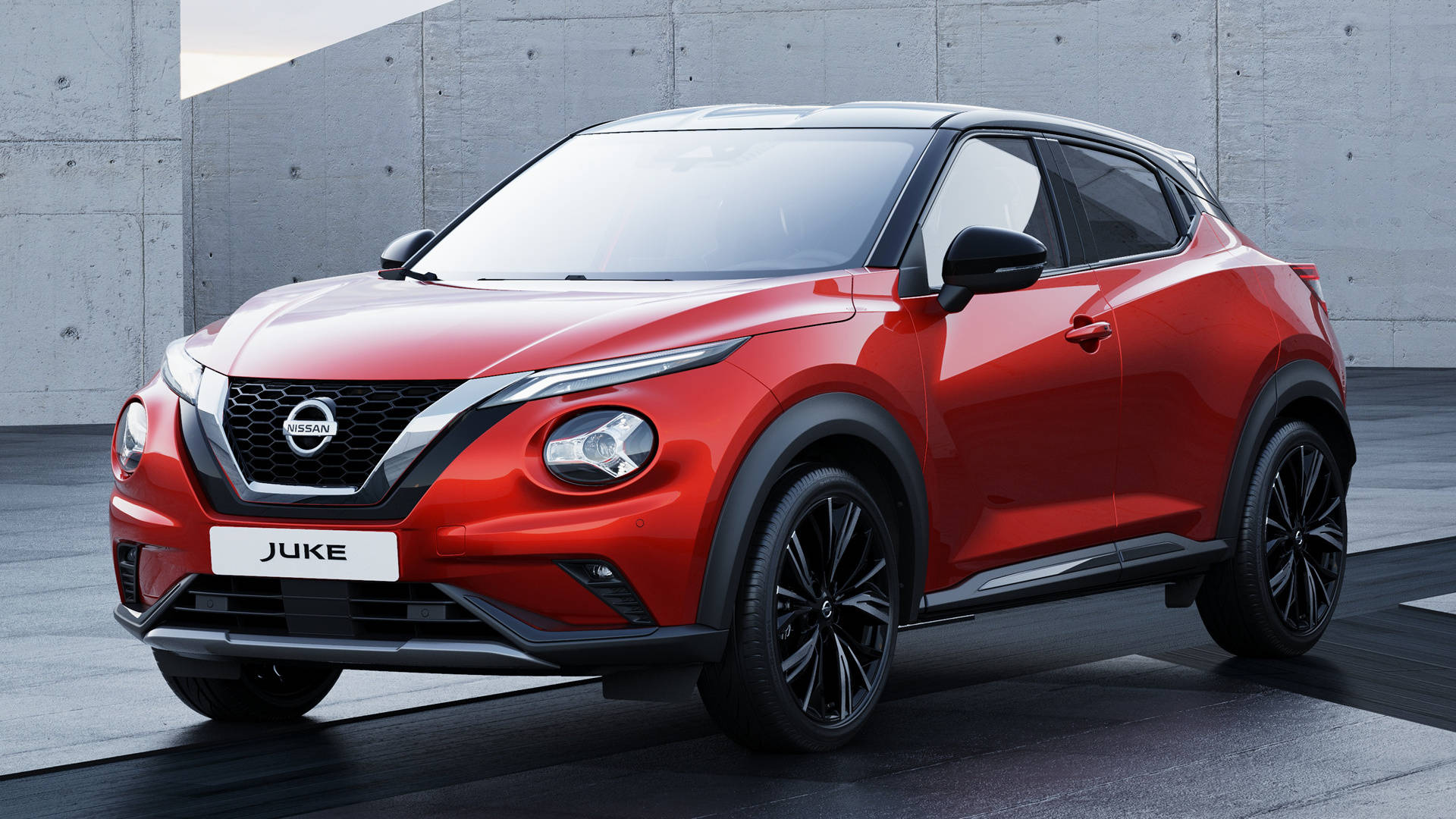 尼桑GTR小型車型 壁紙 — 一輛充滿活力的紅色日產Juke SUV，帶有黑色飾邊，在明亮的攝影棚燈光下，大膽地矗立在簡約的混凝土牆前。