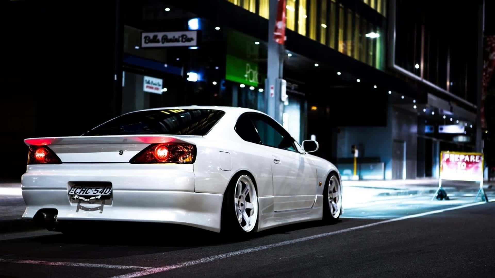 尼桑Silvia S15城市街道 壁紙 — 一輛流線型白色跑車在夜間潮濕的城市街道上，在霓虹燈下閃耀。