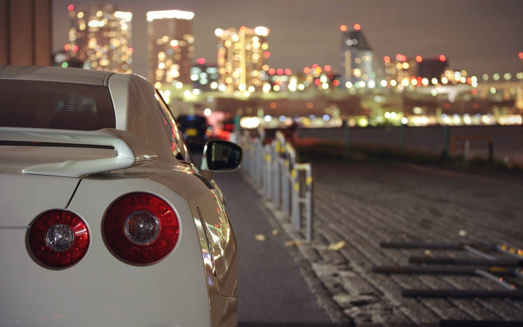 白色跑車夜間停泊，背景有城市燈光