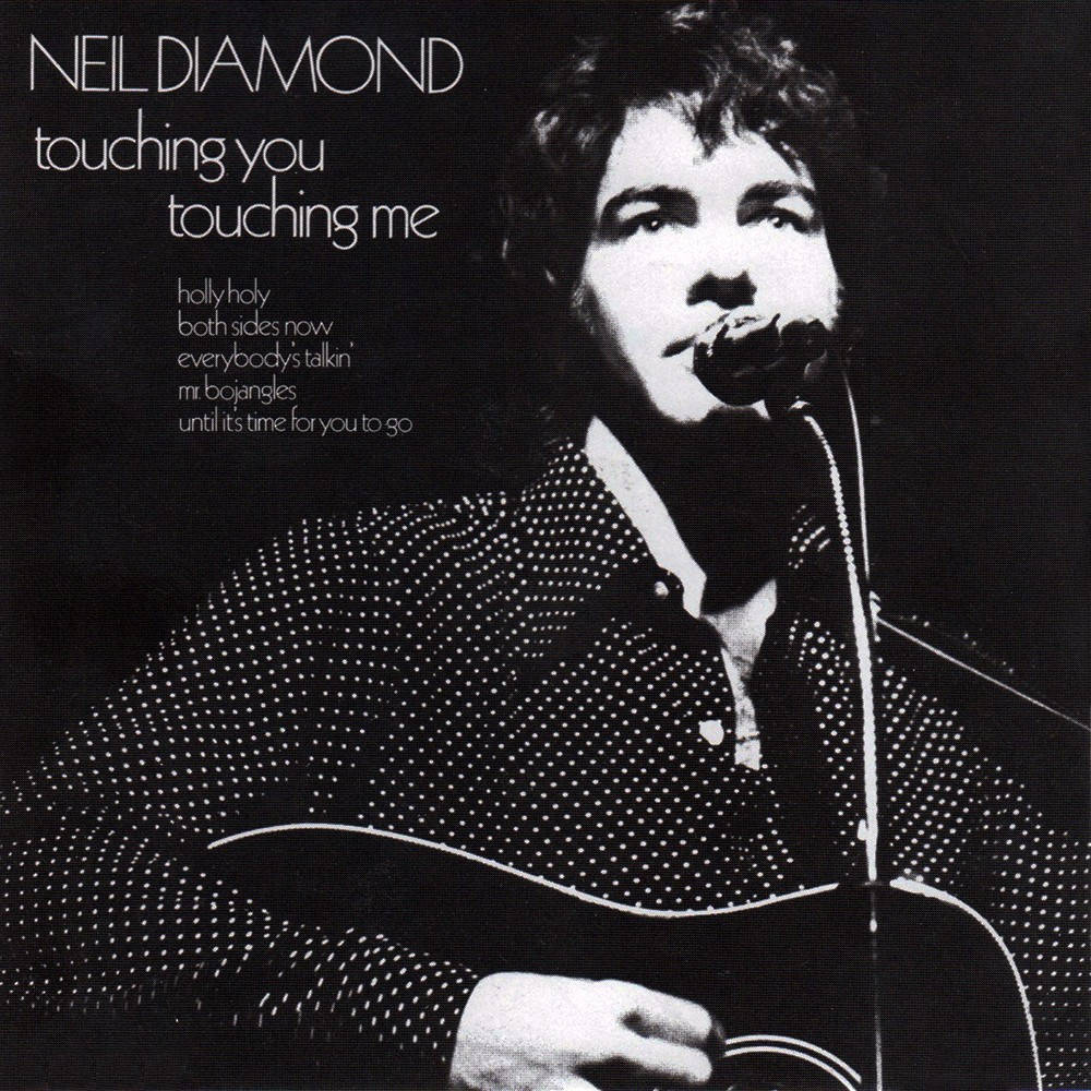尼爾·戴蒙德與經典專輯《Touching You, Touching Me》 壁紙 — 一張尼爾·戴蒙德（Neil Diamond）手持木結他對著咪高峰唱歌的黑白照片。